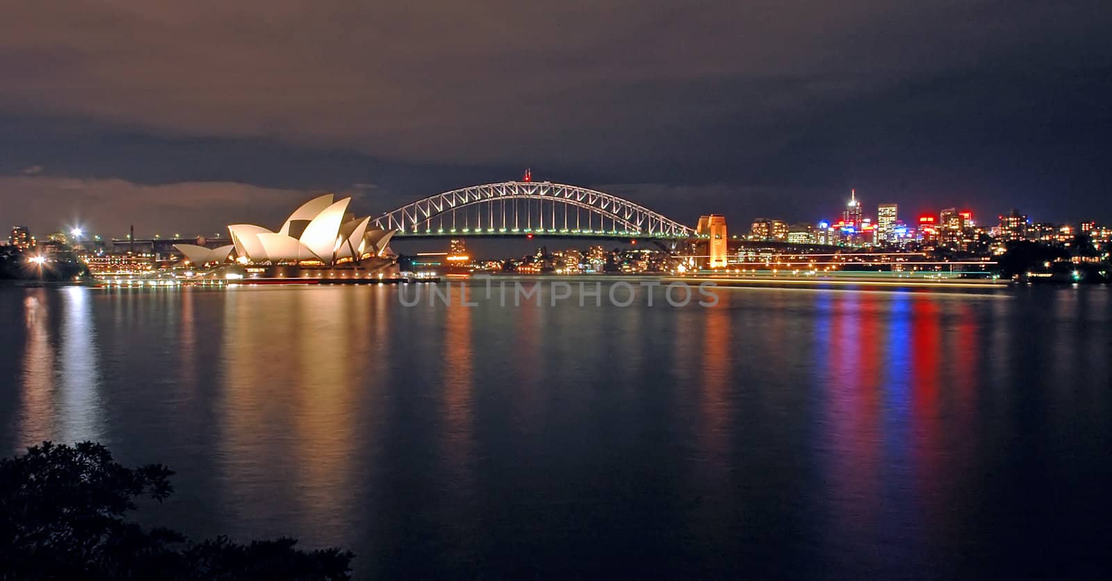 opera house, harbour bridge and north sydney at night; photo taken from royal botanic gardens