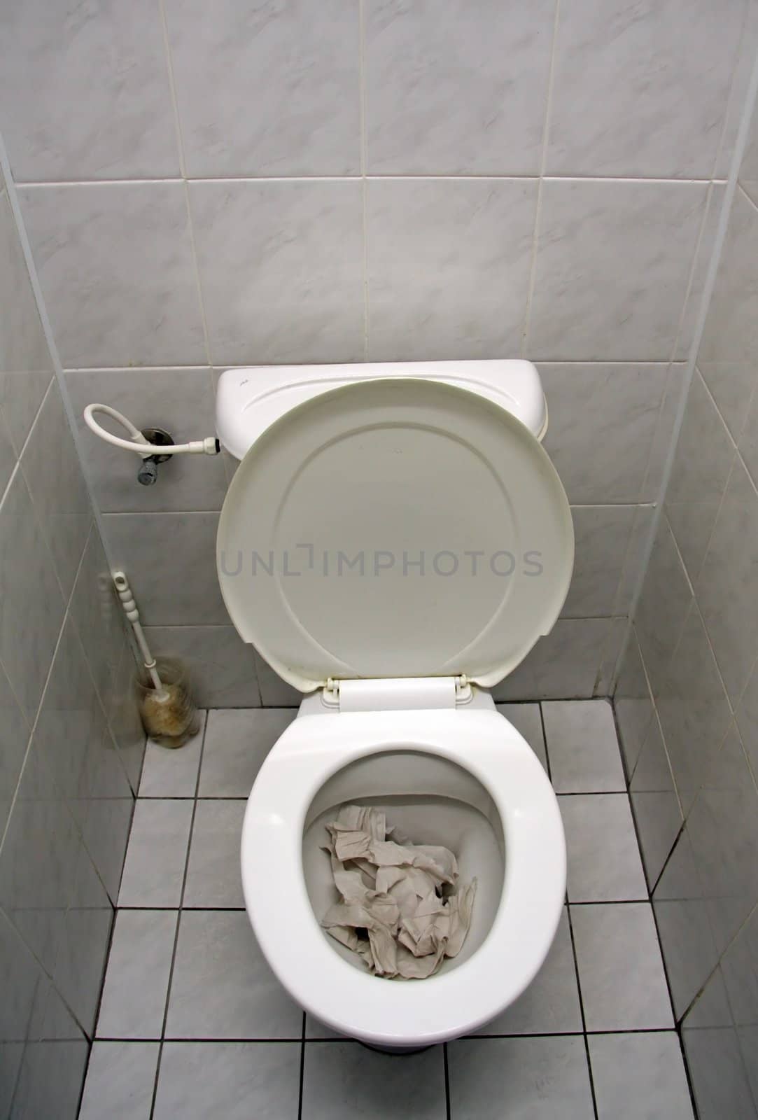 white rest room, toilet in the middle, stacked with toiled paper