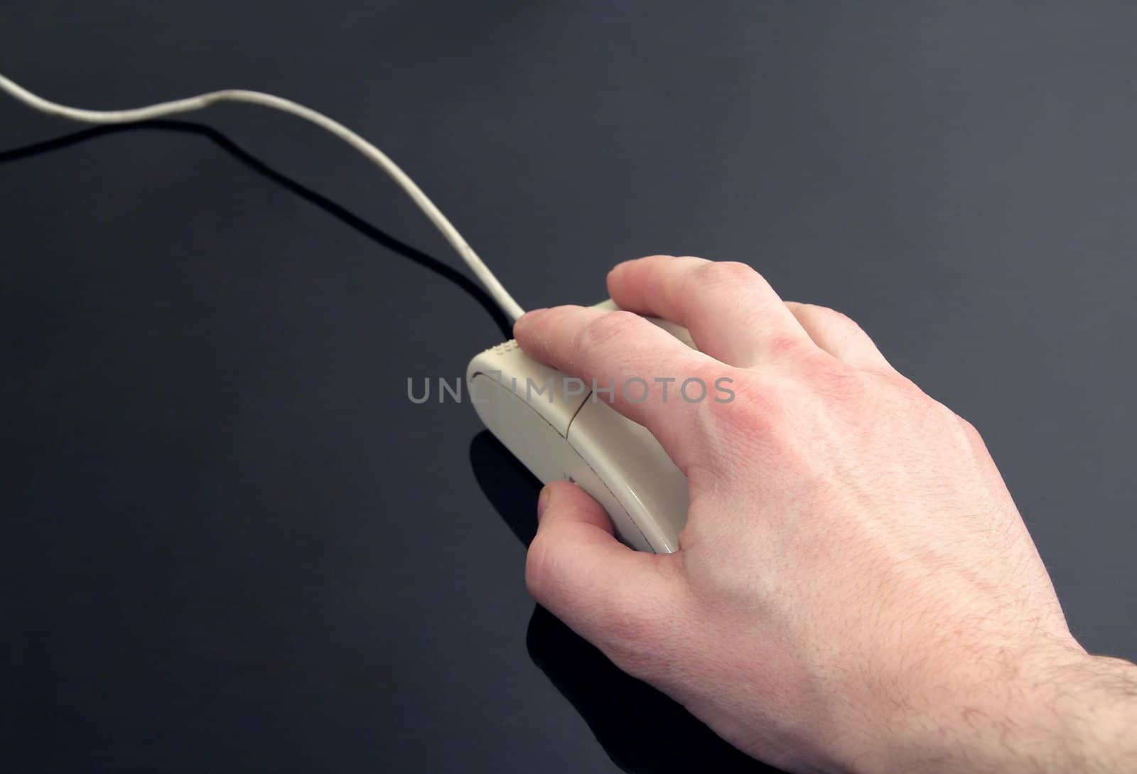 man's hand holding computer mouse, black reflective background