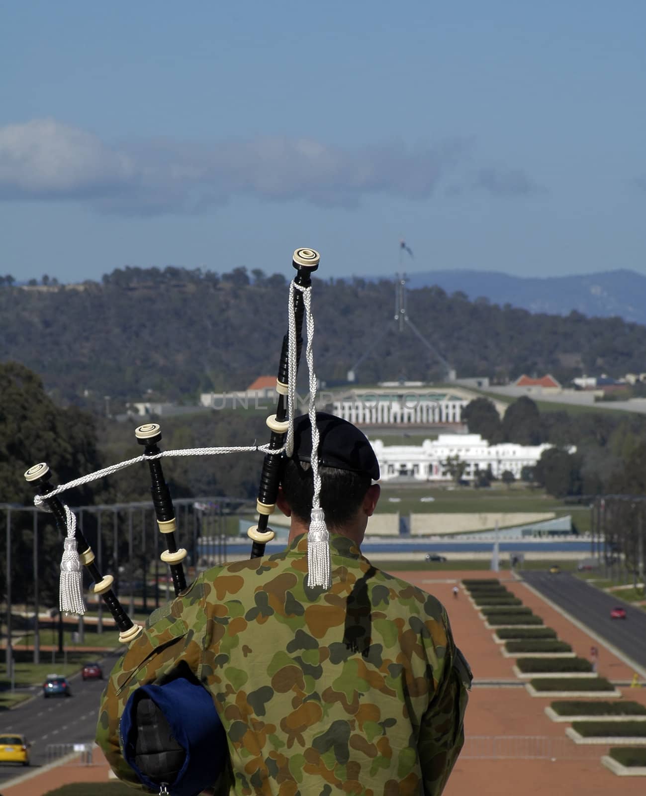 australian soldier playing bagpipes in front of Anzac Parade and Capital Hill in Canberra