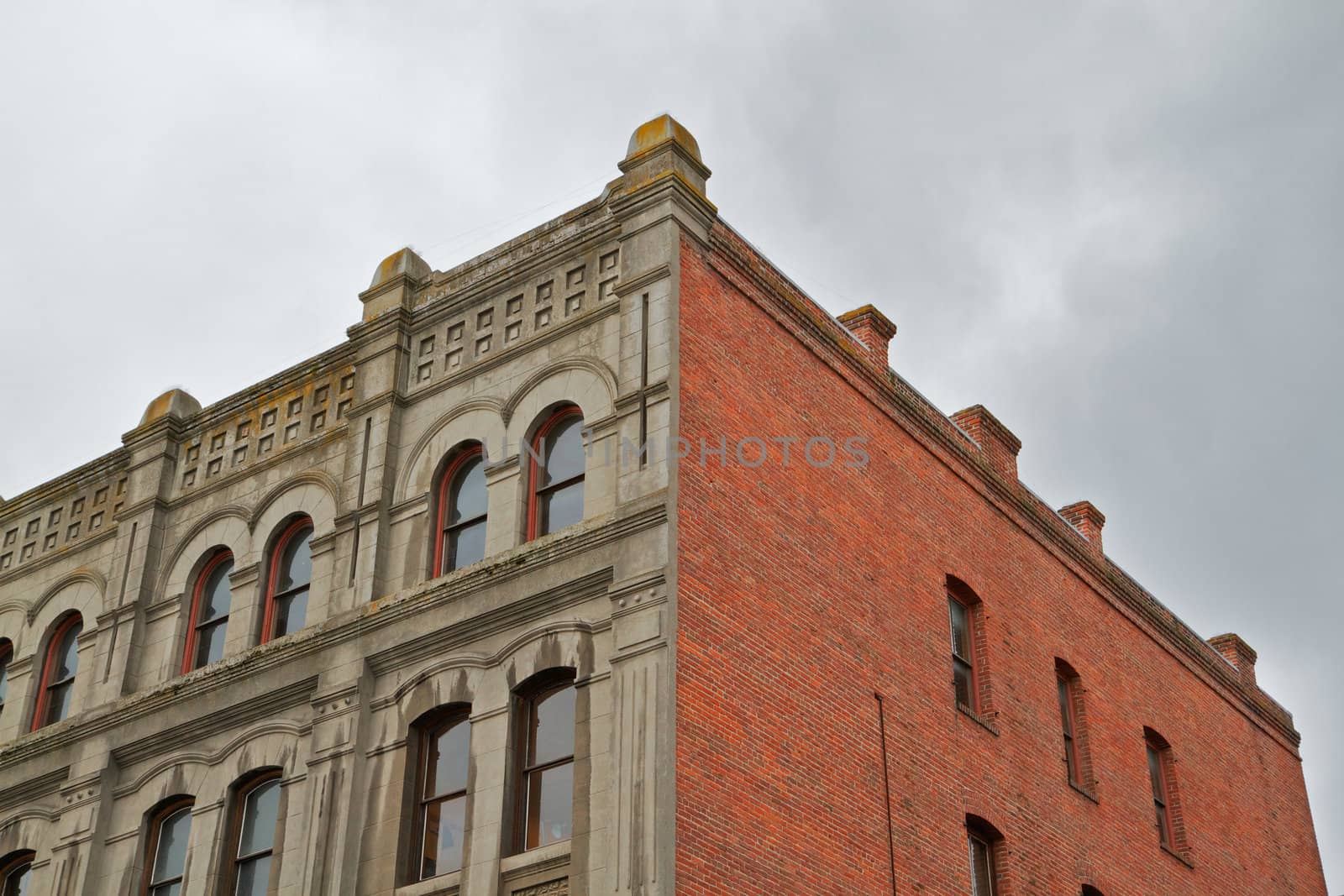 Old red brick building with a stone facade against a cloudy sky