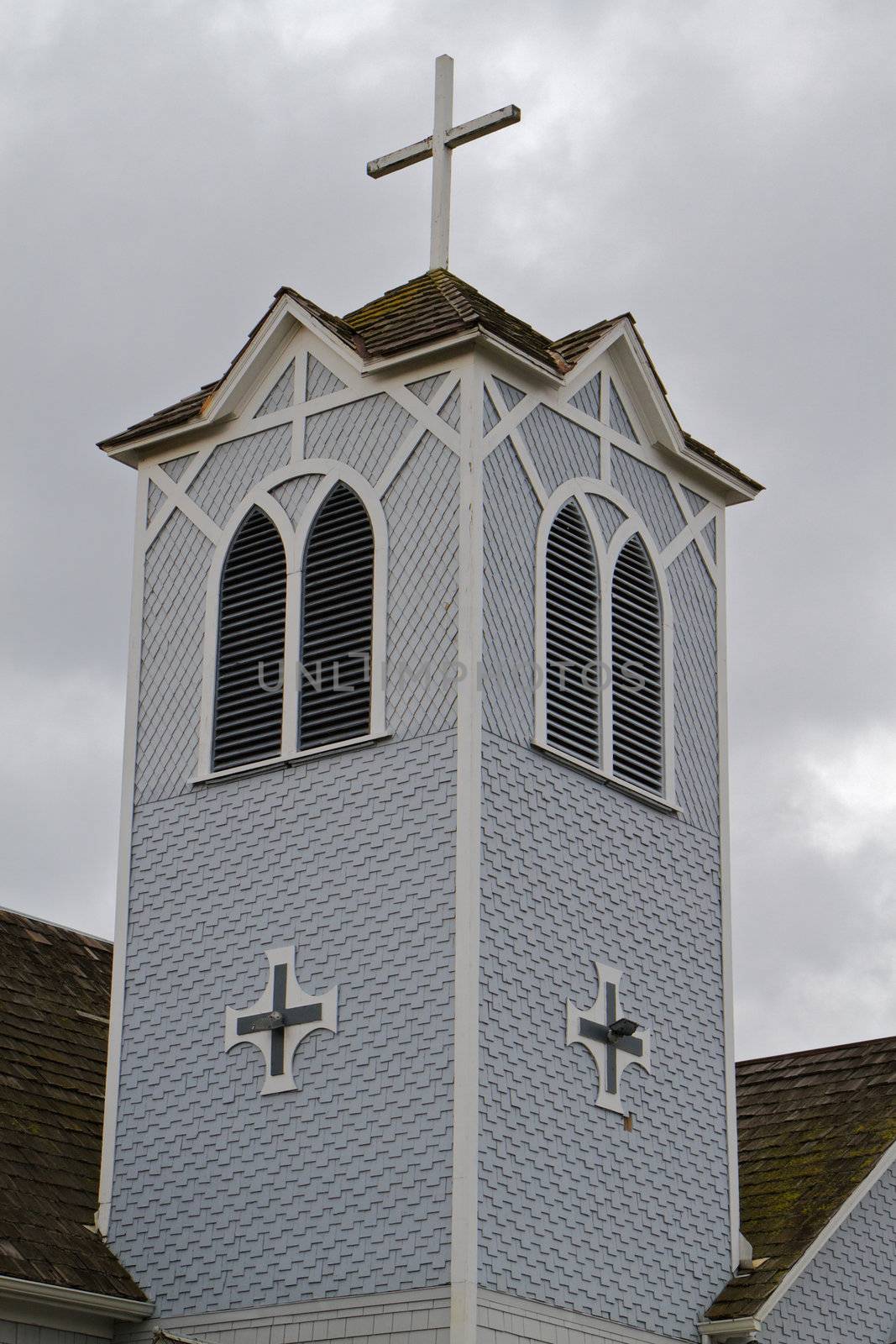 Gray and white wood church tower against a gloomy cloudscape