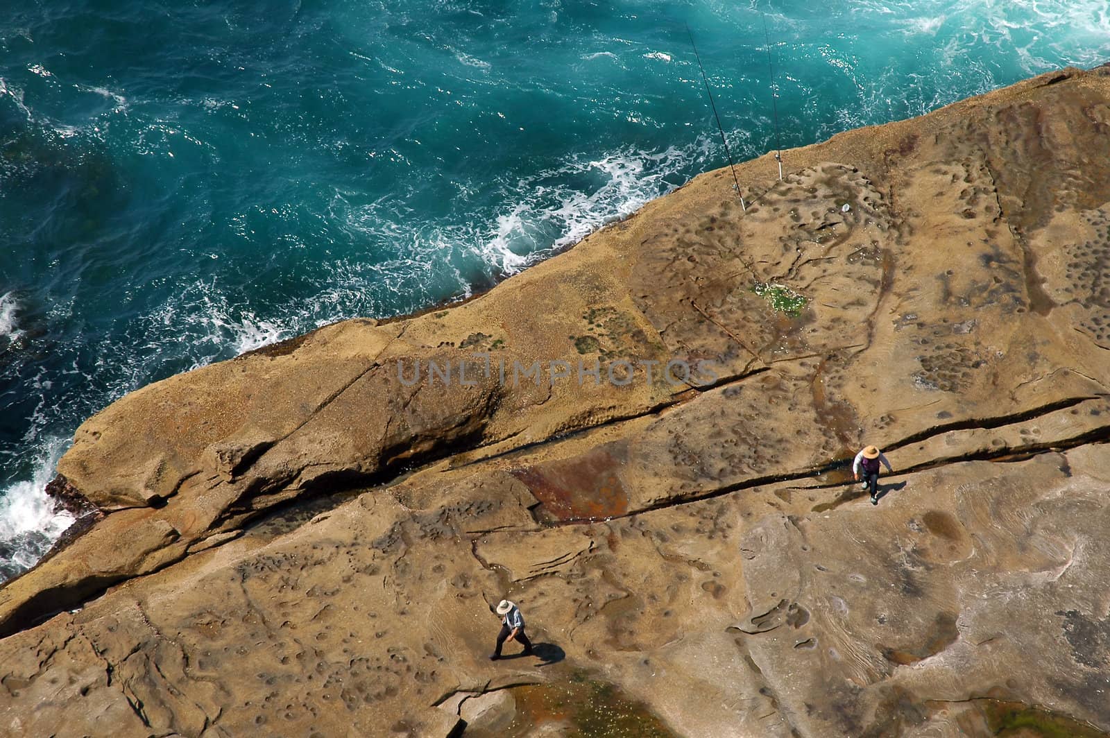 rocky ocean coastline, two fisherman and angling rods