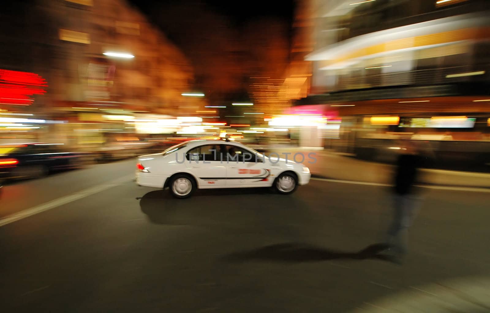 taxi in curve, motion blur, pedestrian crossing a street, night scene