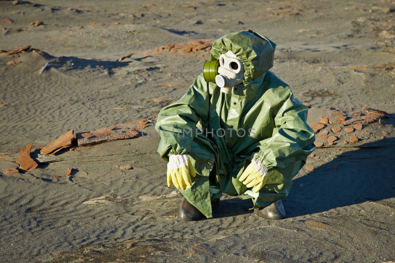 Scientist in a green protective suit and gas mask sitting on the slag