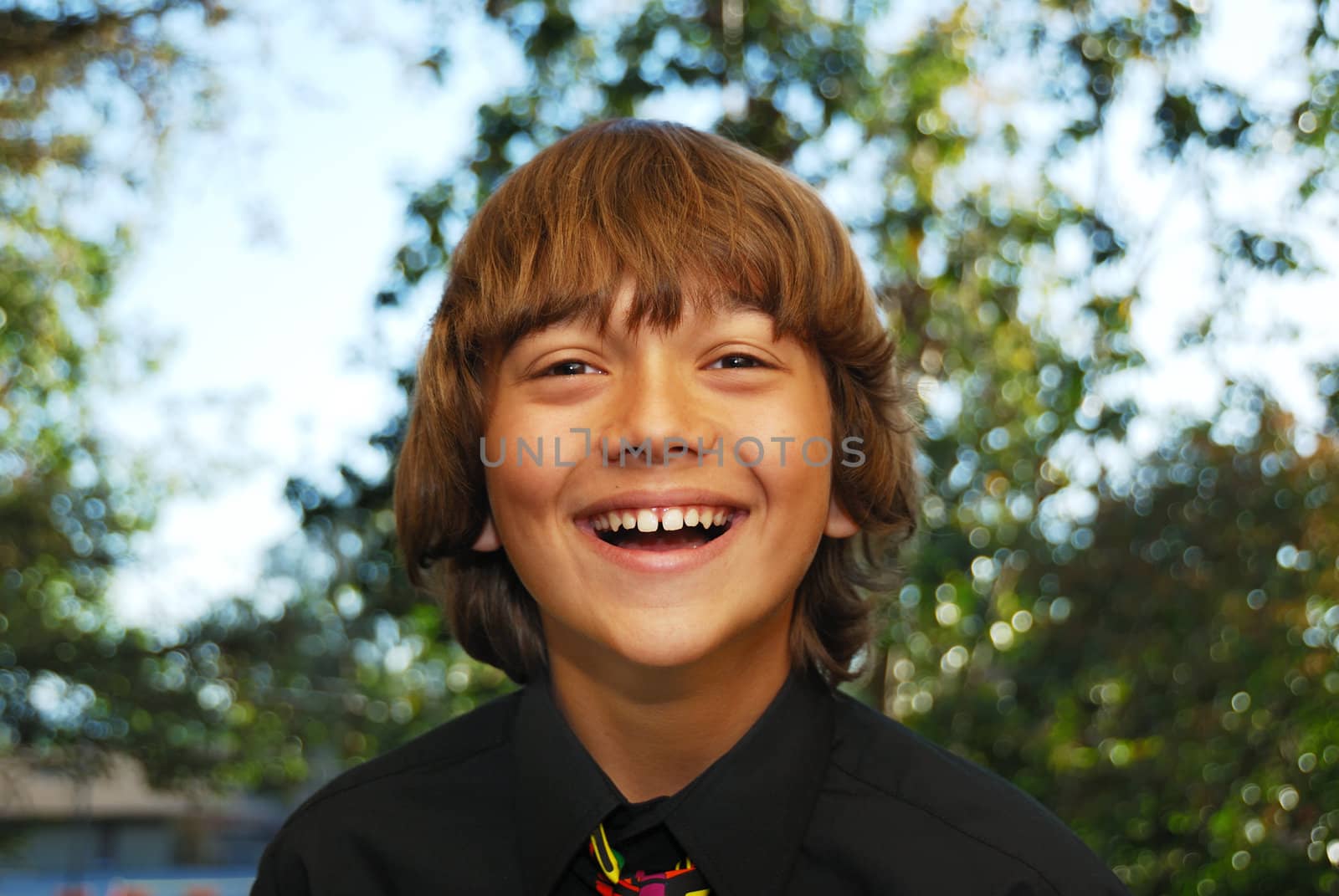 Smiling teenager dressed up in a black shirt and tie.