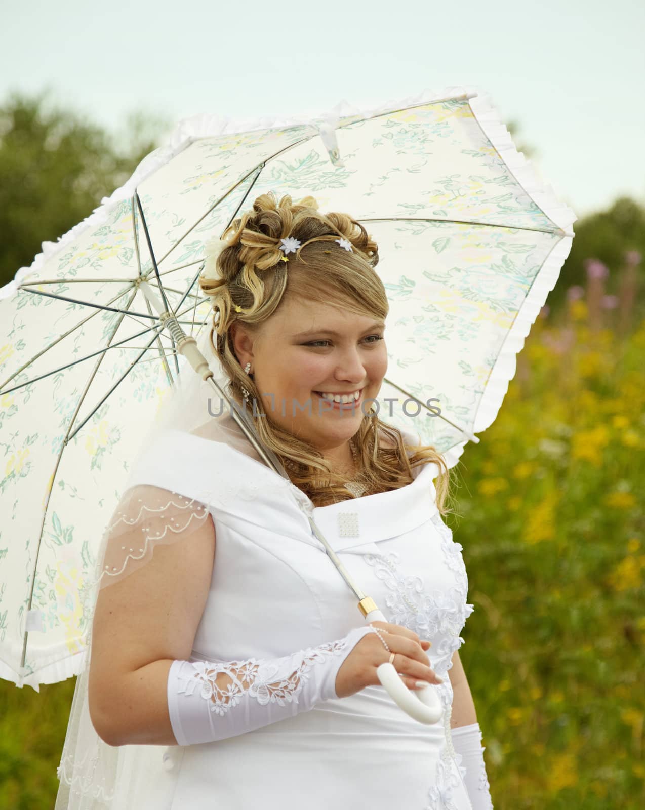 Happy bride with a parasol on the nature
