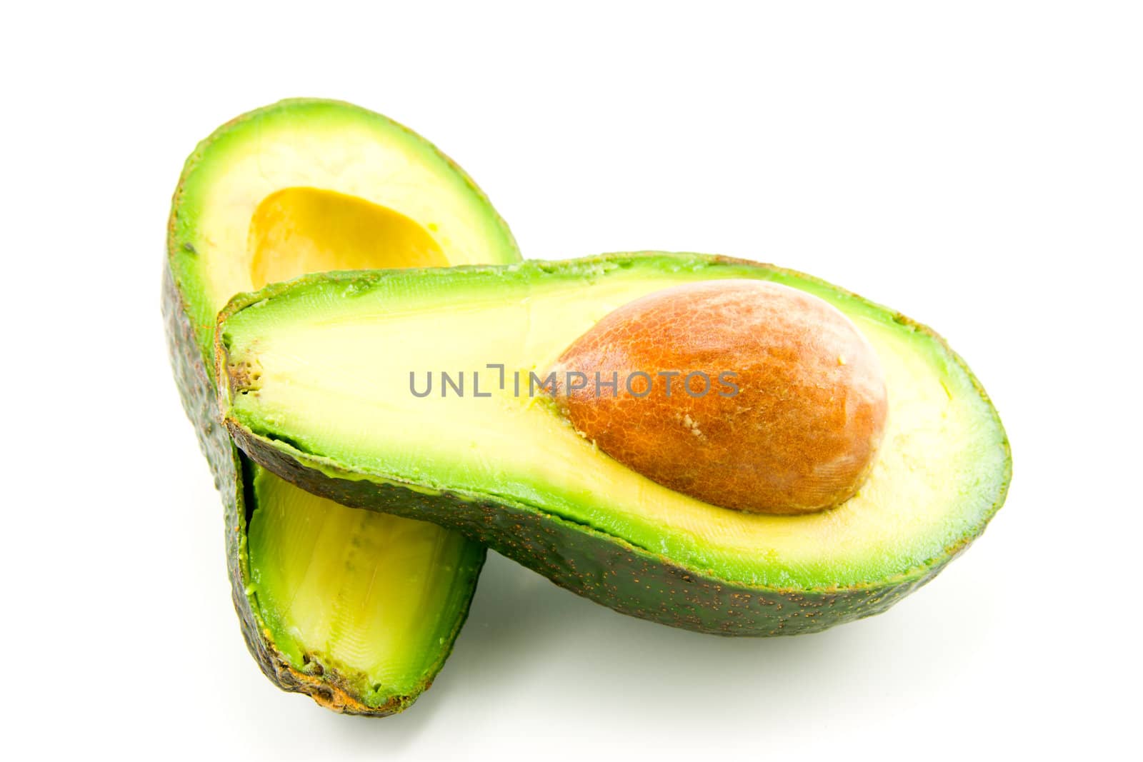 single dark green avocado fruit split in half and showing the kernel on a white background