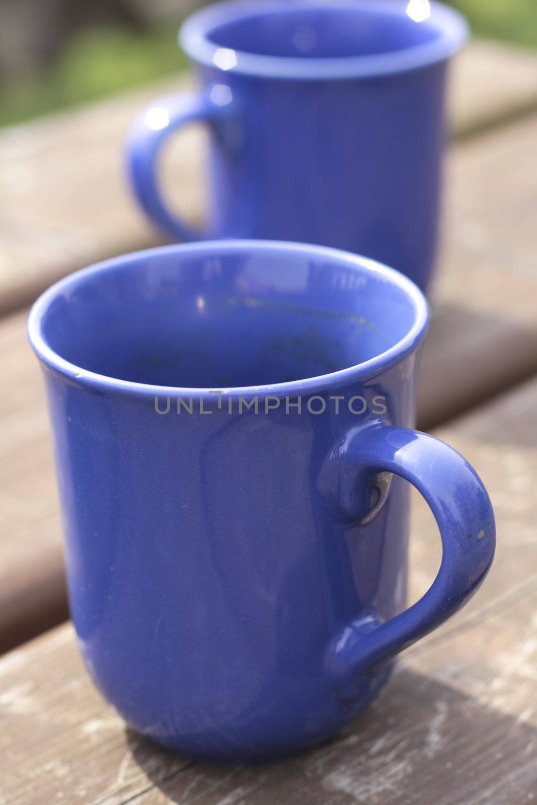two blue empty ceramic beakers on a wooden table