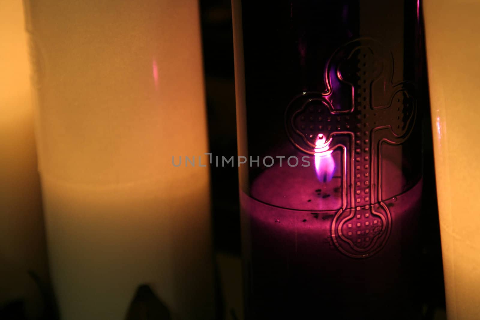 A close-up of a purple candle with a cross engraving on it.