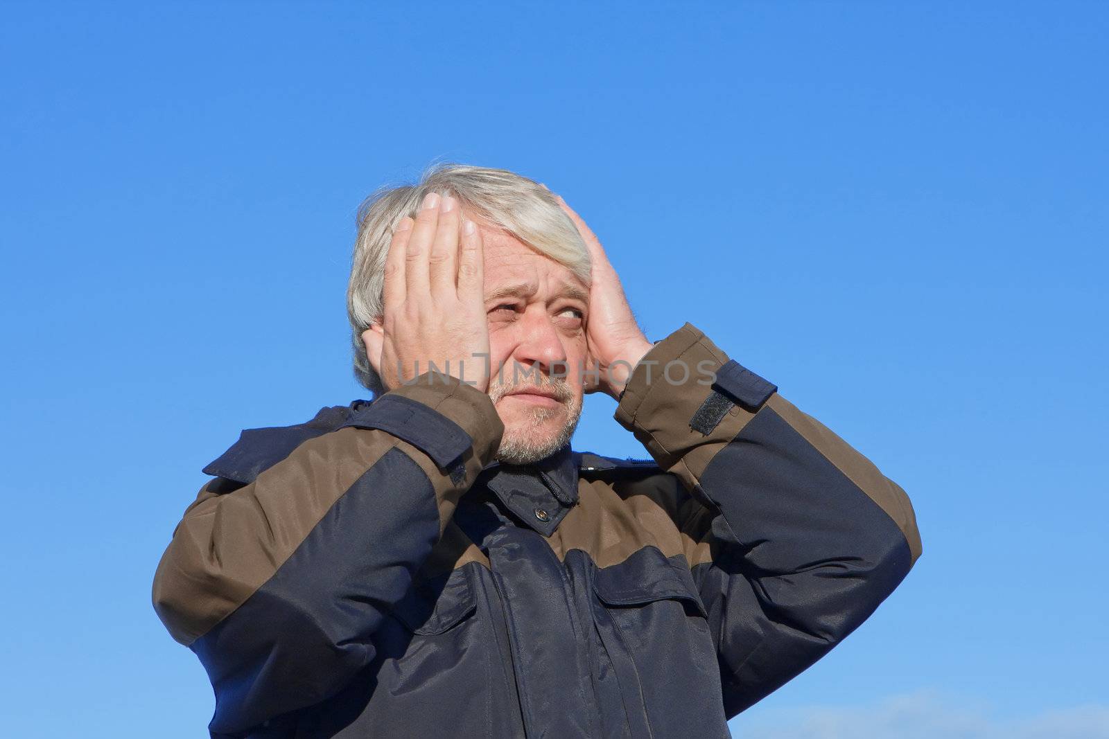 Portrait of mature concerned man with grey hair on blue sky of the background.