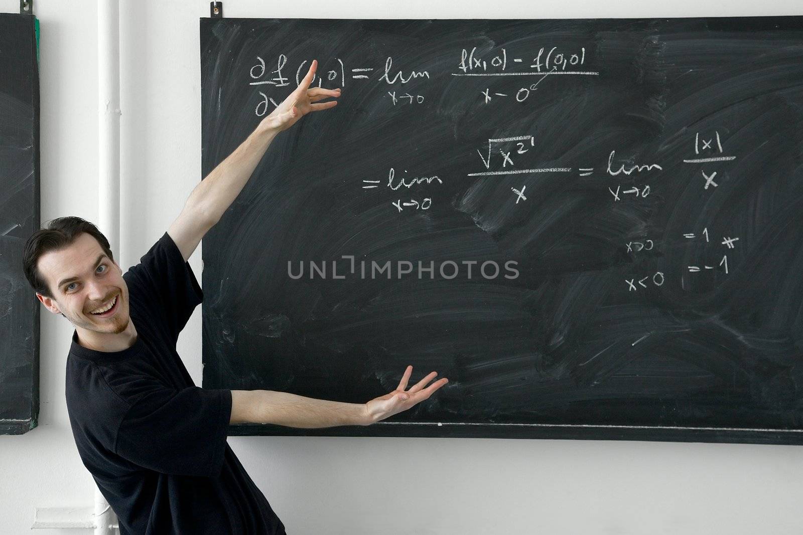 Young man showing math results on the blackboard happily