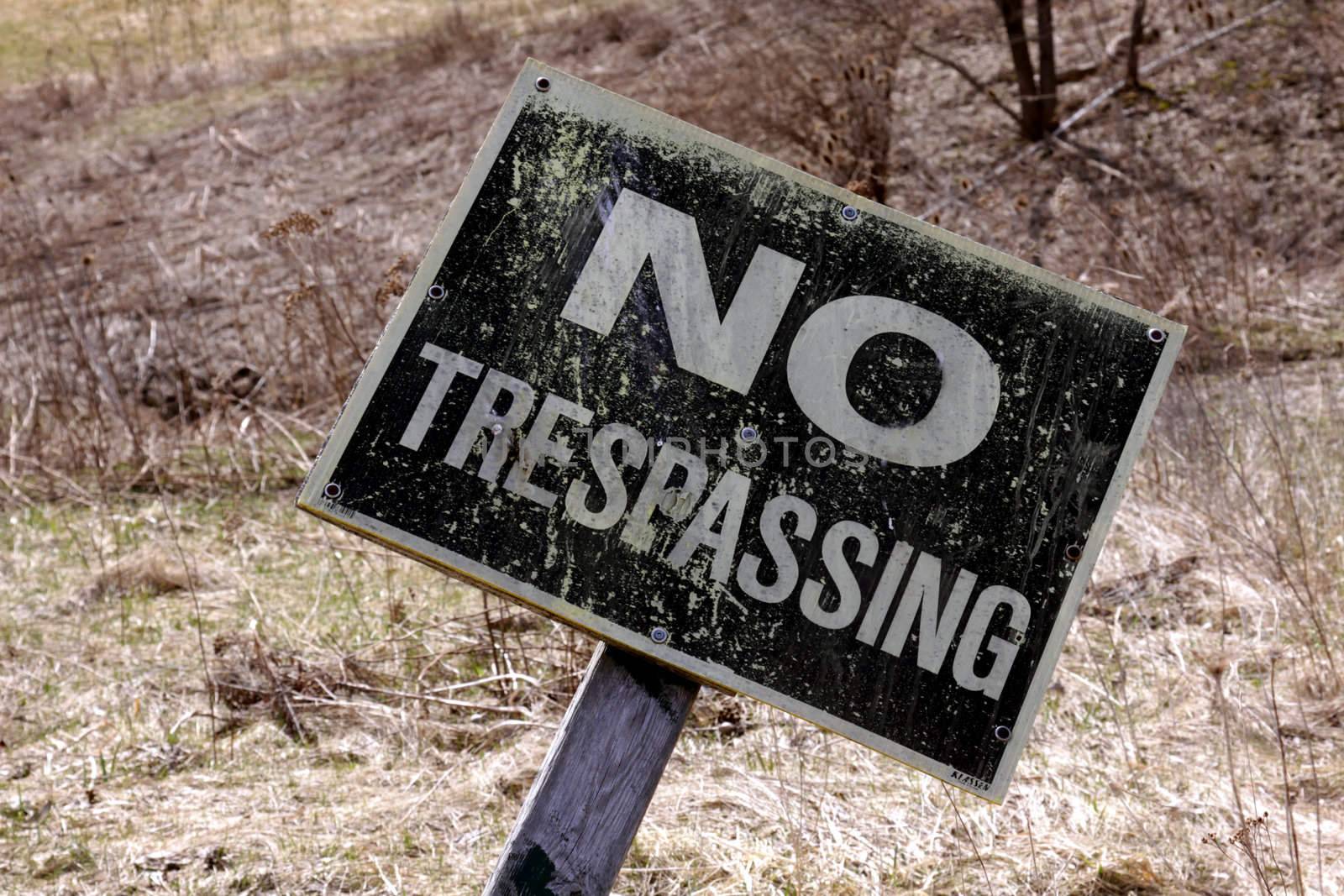 A close-up of a crooked no trespassing sign.