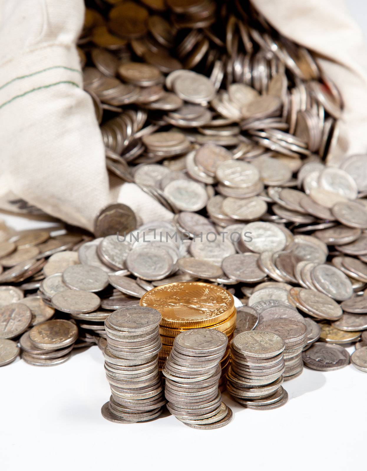 Linen bag of old pure silver coins used to invest in silver as a commodity with a selection of Golden Eagle gold coins