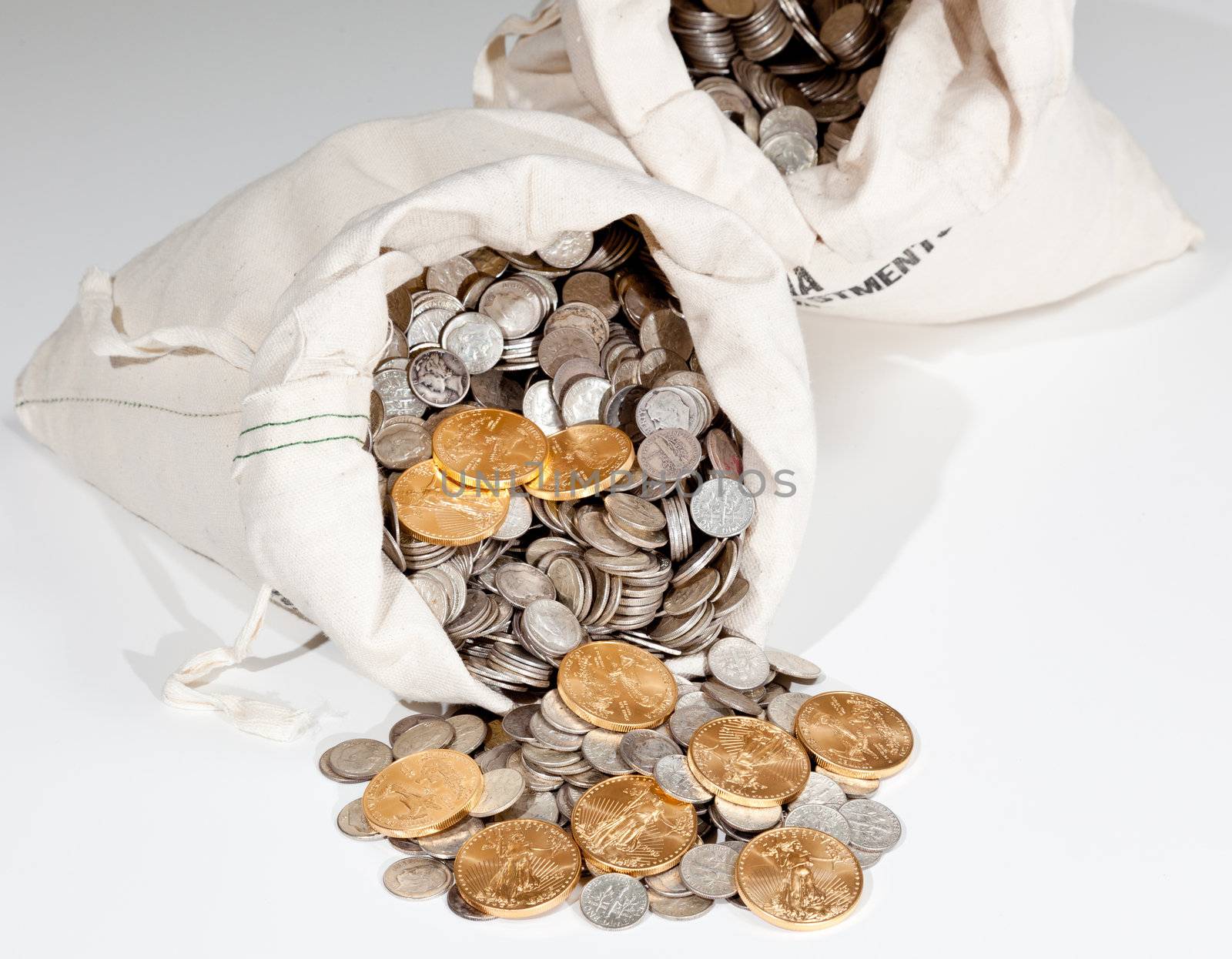 Linen bag of old pure silver coins used to invest in silver as a commodity with a selection of Golden Eagle gold coins