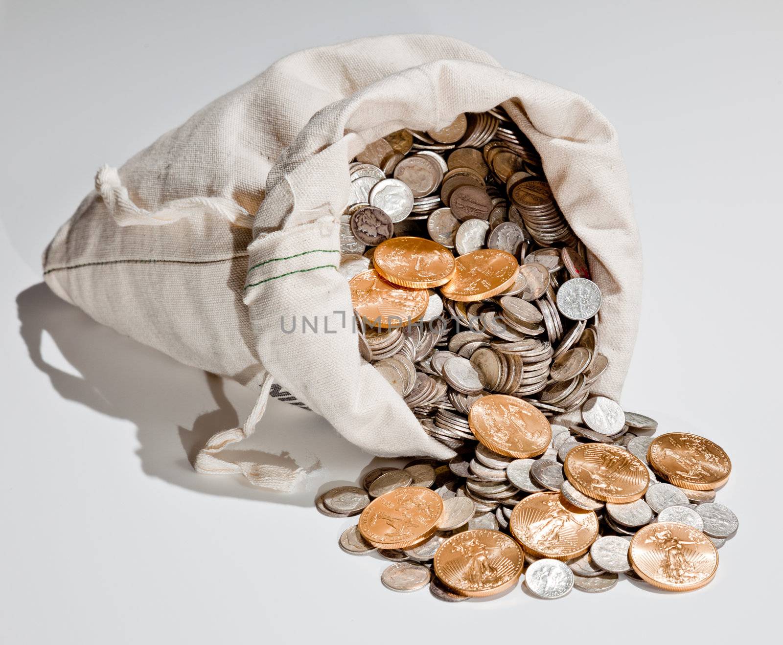 Linen bag of old pure silver coins used to invest in silver as a commodity with a selection of Golden Eagle gold coins