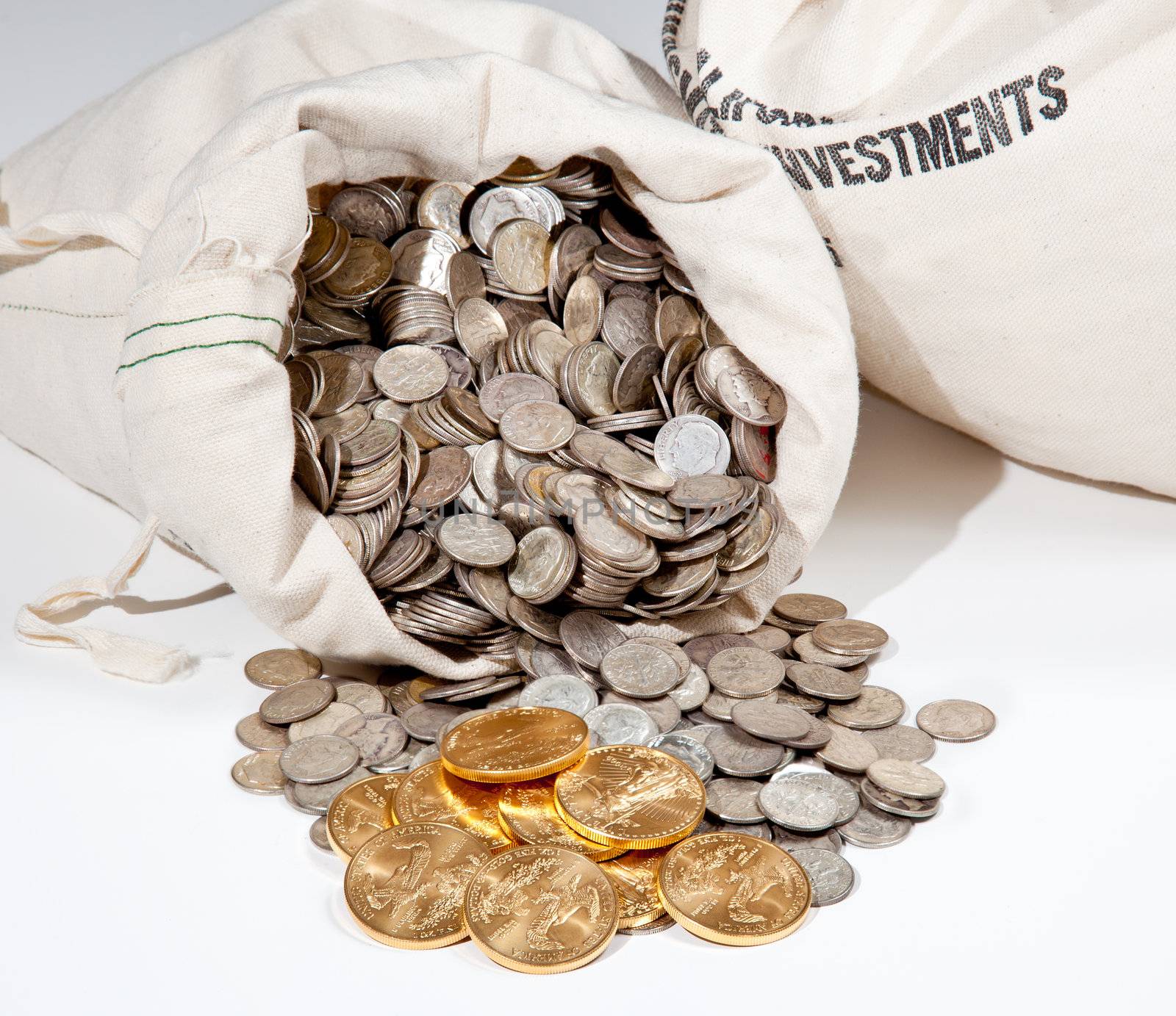 Linen bag of old pure silver coins used to invest in silver as a commodity with a selection of Golden Eagle gold coins