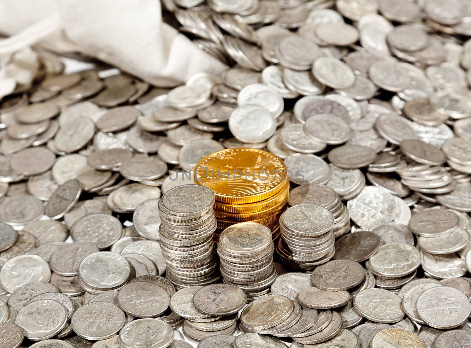 Linen bag of old pure silver coins used to invest in silver as a commodity with a selection of Golden Eagle gold coins