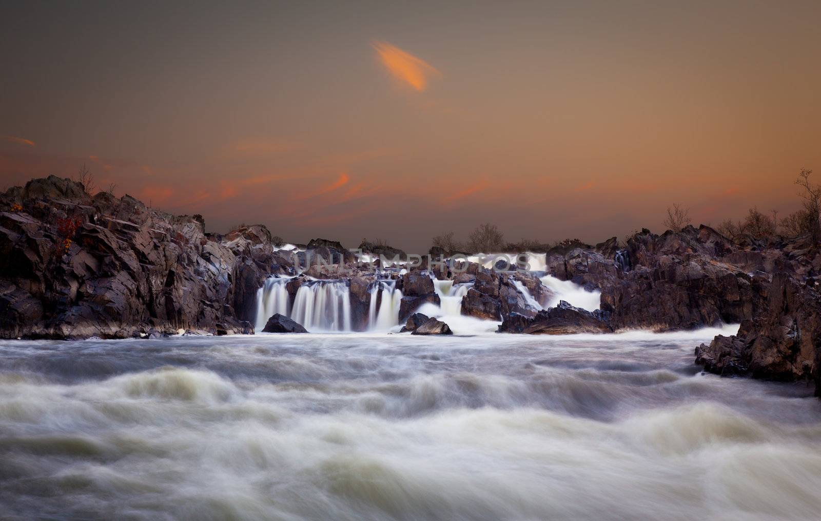 Waterfalls on the Potomac river near Washington DC after sunset as the setting sun illuminates the clouds over Great Falls