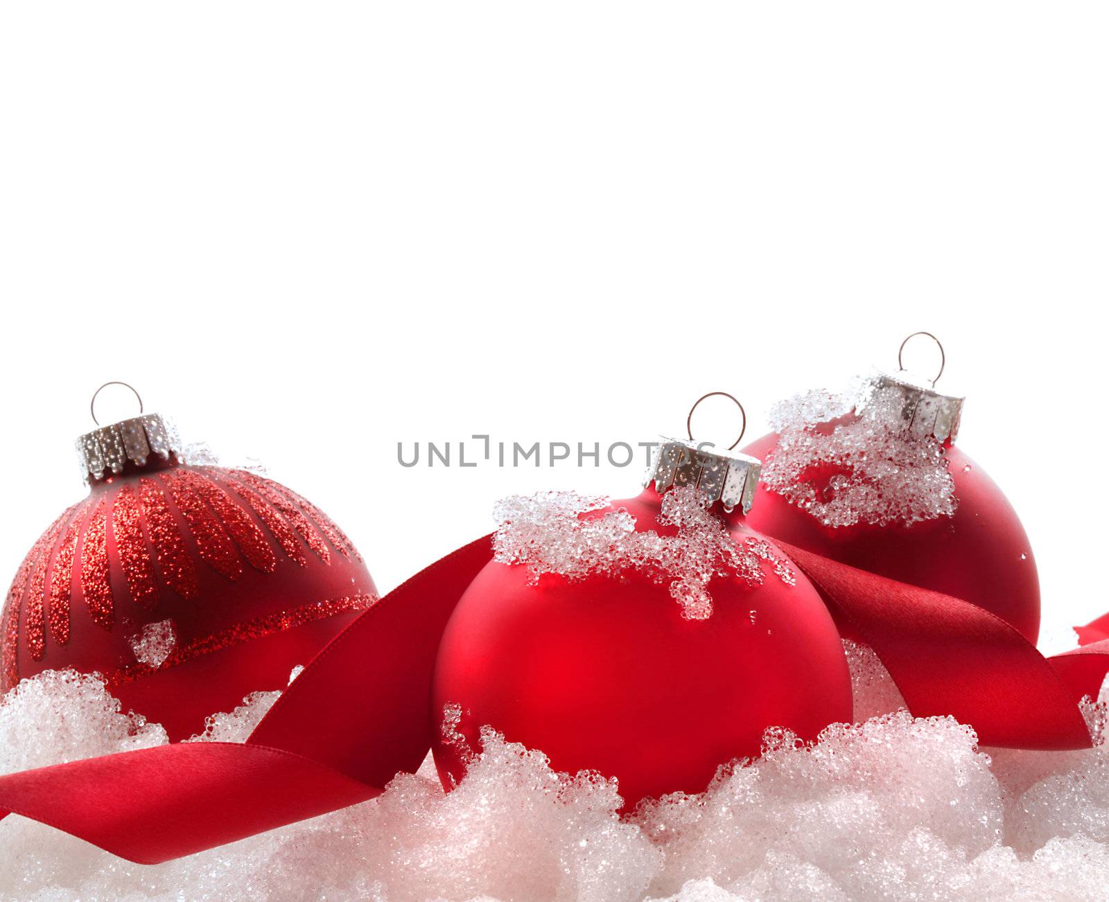 Red christmas balls and ribbon in snow on white background