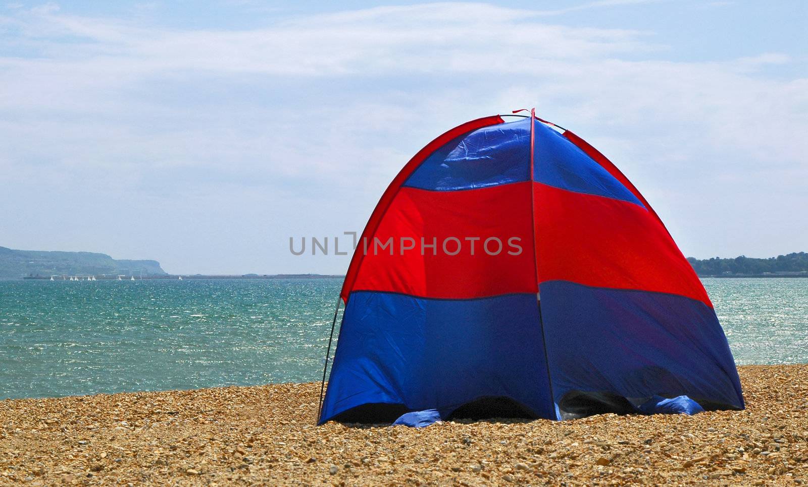 tent pitched on a stony beach (bay is weymouth bay, venue of the 2012 olympic sailing regatta)