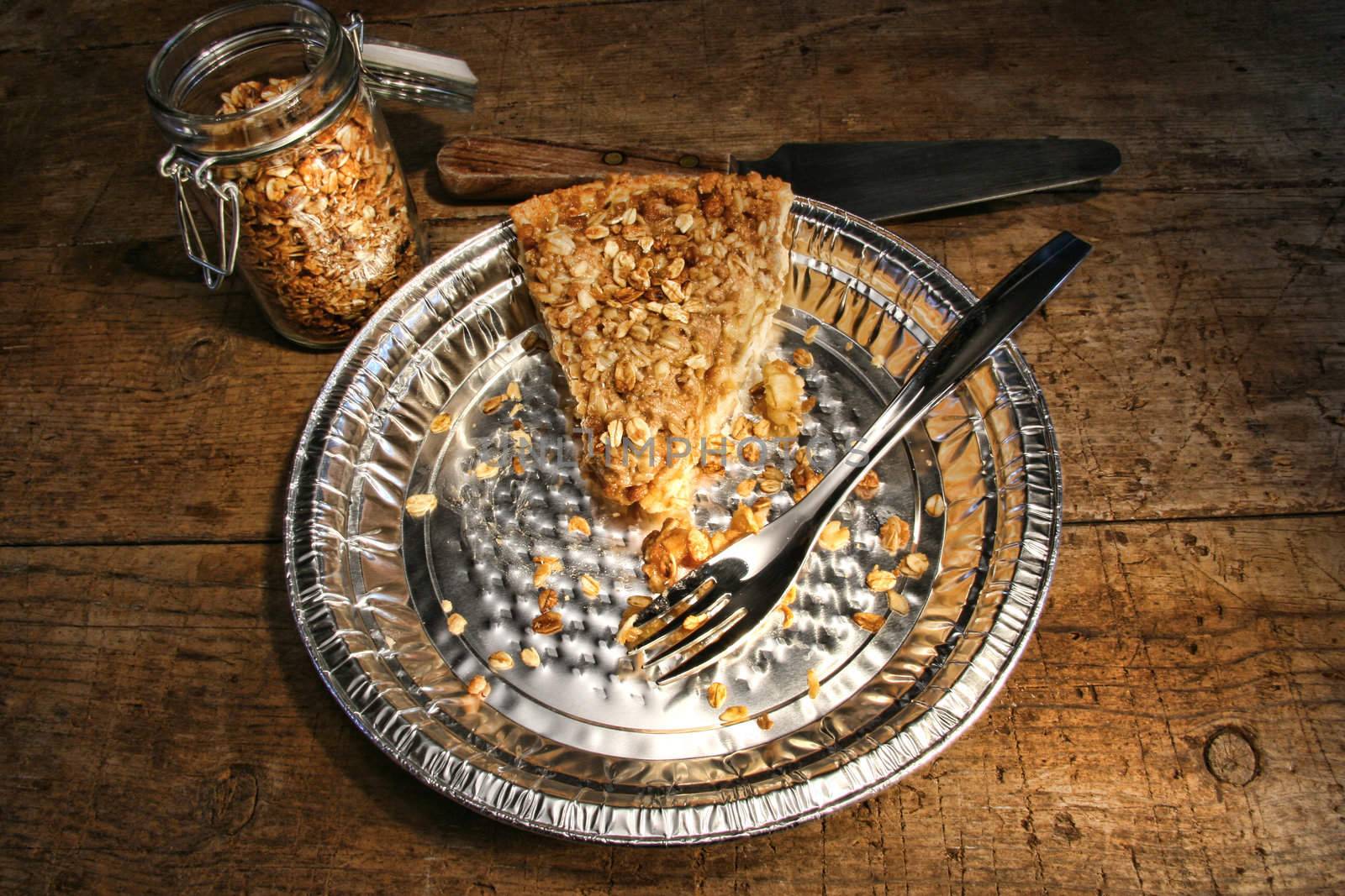 Last piece of apple crumble pie in aluminum  plate on wood
