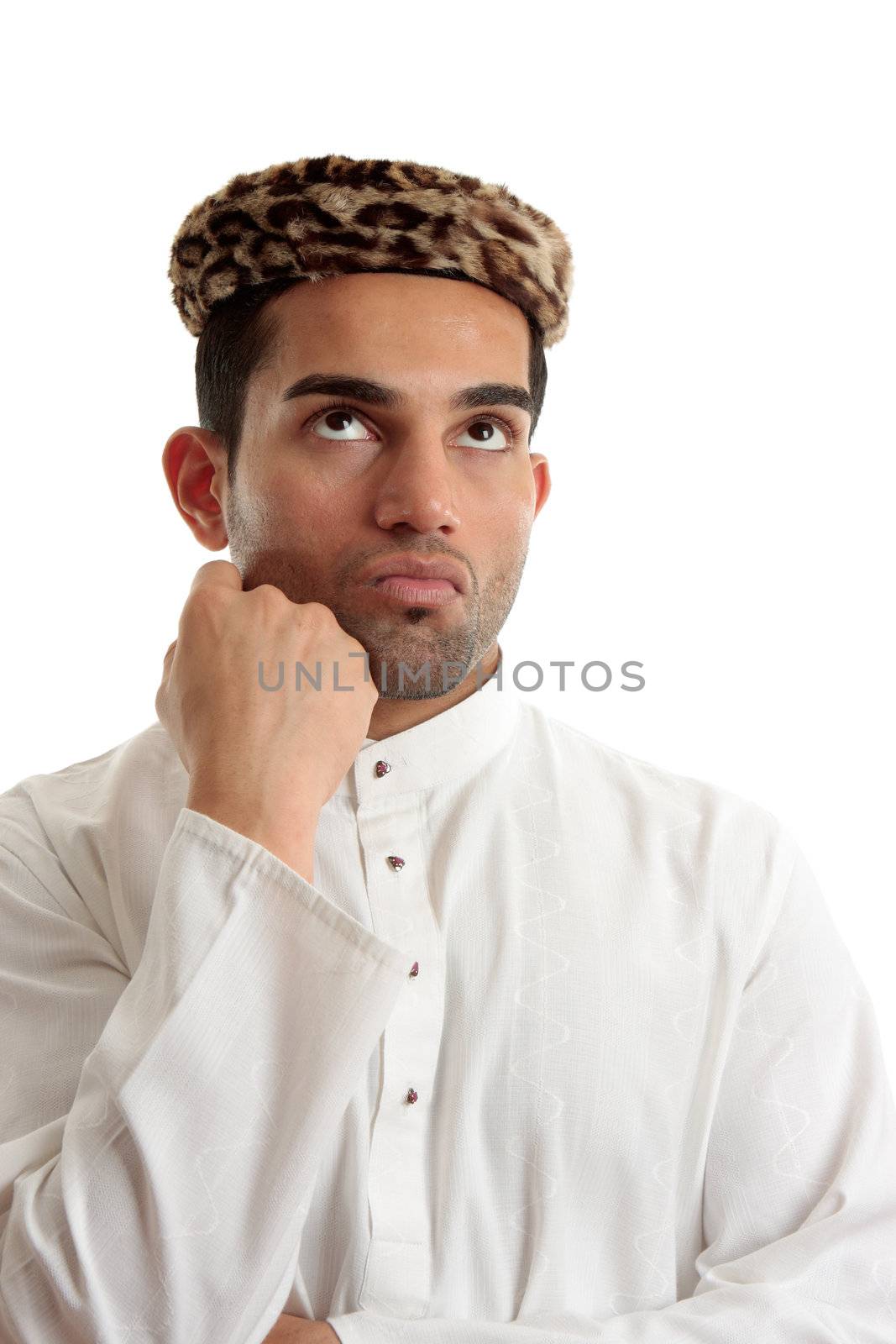 An ethnic man wering a white embroidered robe fastened with claw set rubies and wearing vintage leopard skin hat.  He is looking up and thinking or pondering.   Space for copy.   White background.