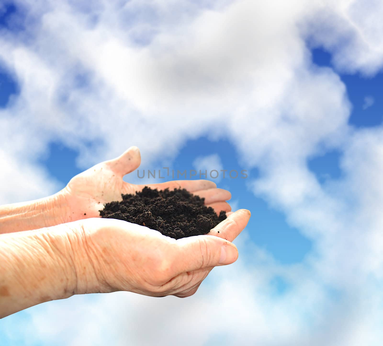 Soil in hands, sky wiht clouds