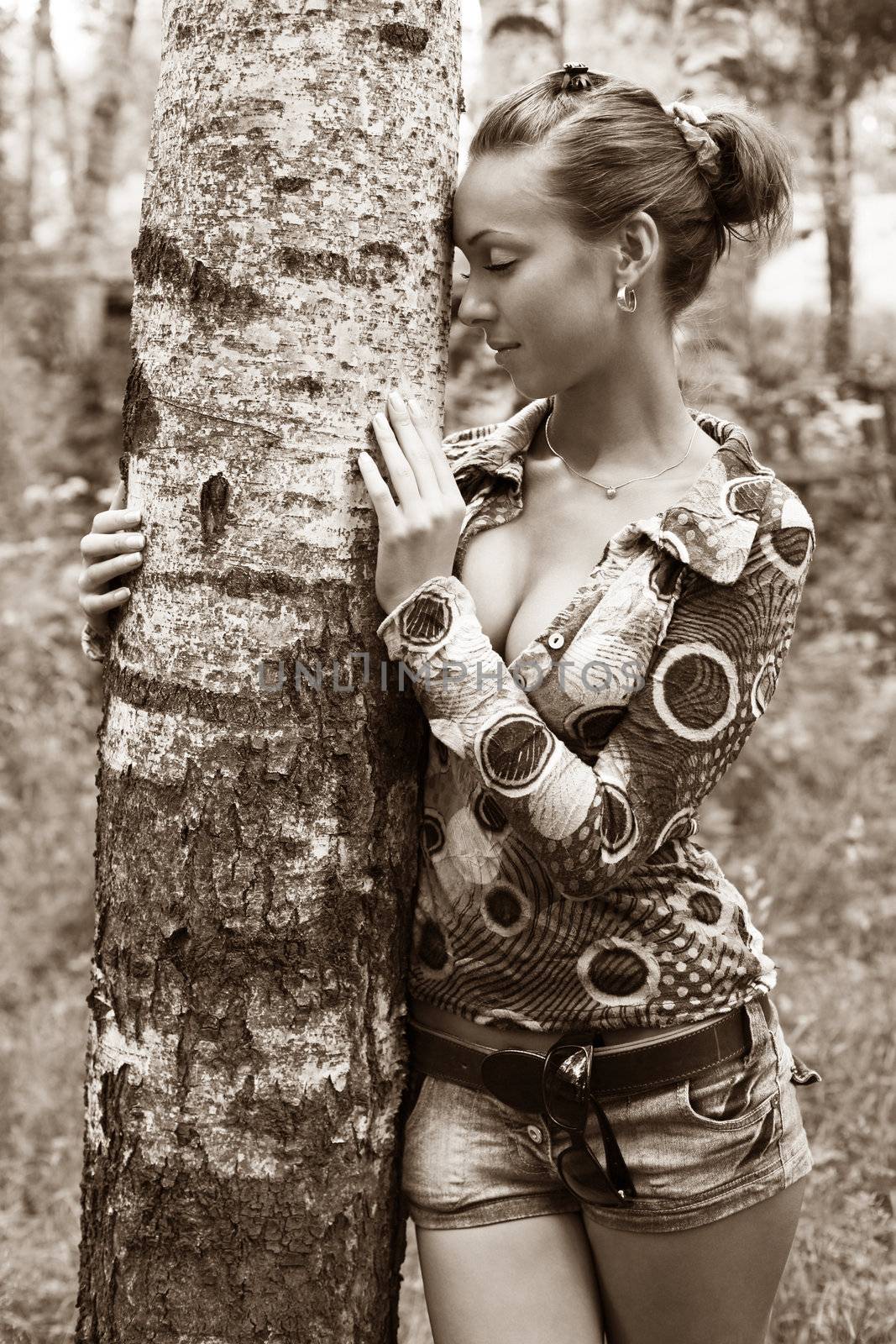 Young woman leaning against birch tree in forest