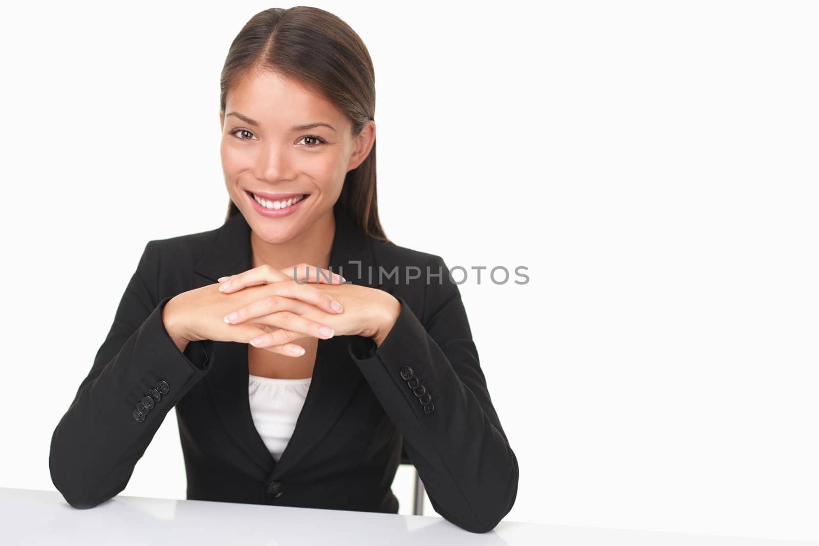 Woman sitting at table smiling at camera. Beautiful young businesswoman (mixed Asian Chinese / white Caucasian).