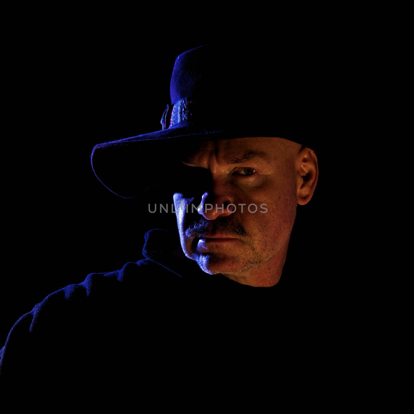 Photo Illustration of a cowboy lit by moonlight and a campfire isolated on black