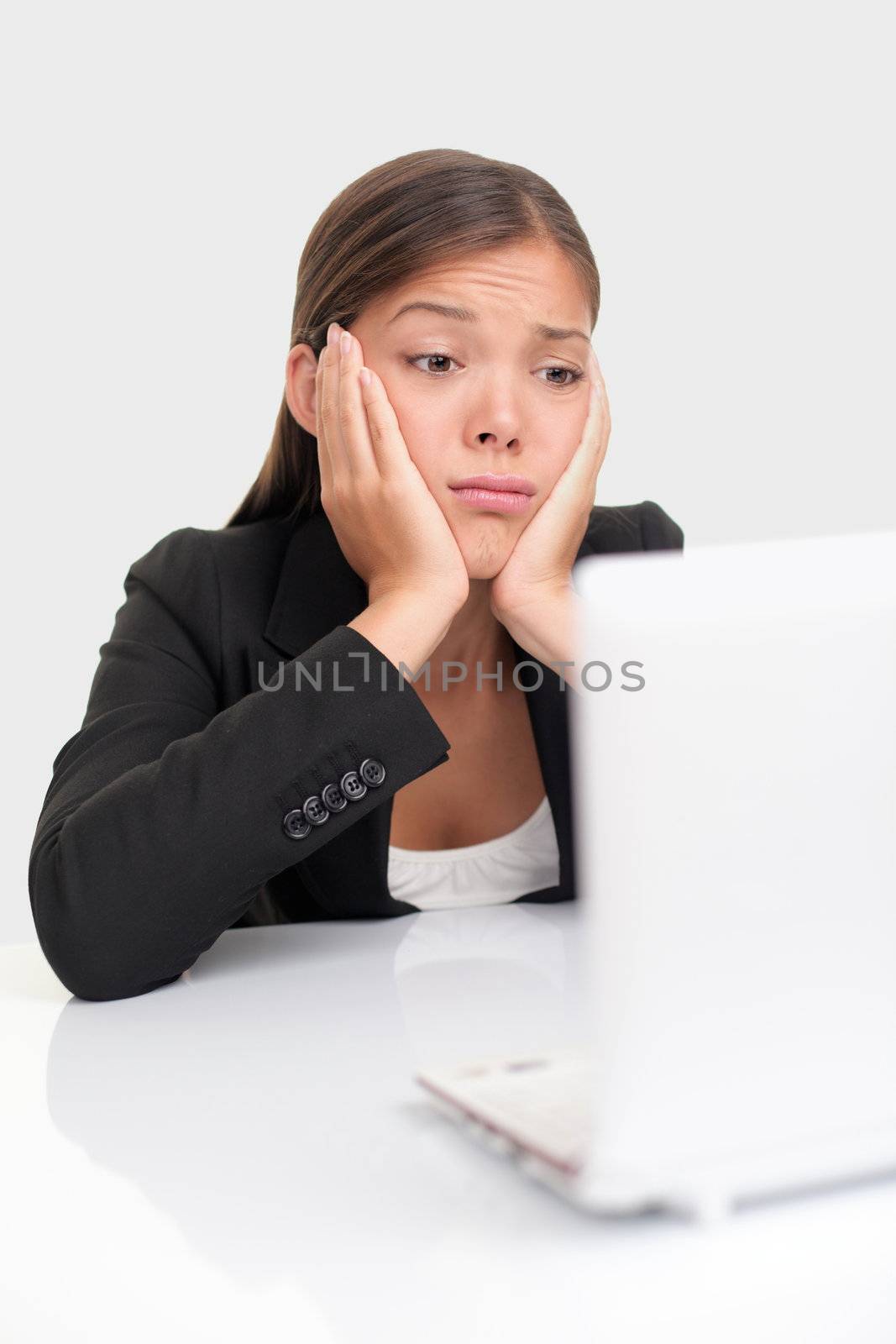 Bored businesswoman working on laptop computer looking very boring at the pc.