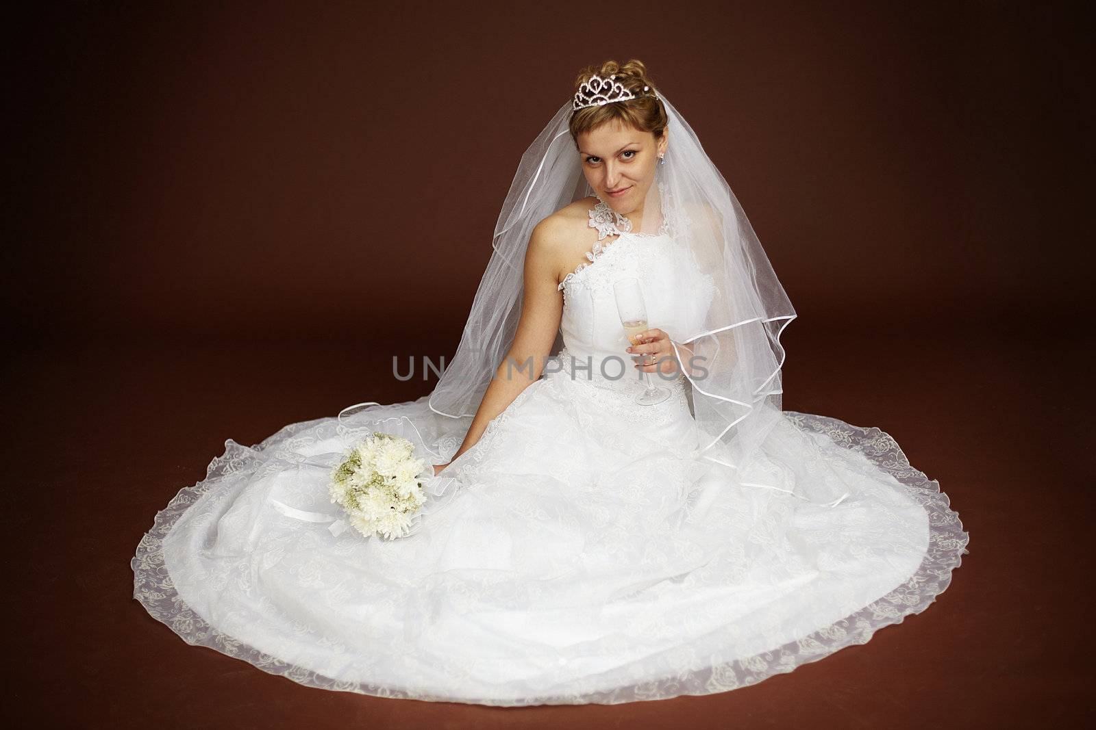 Young bride in a white dress sitting on a brown background