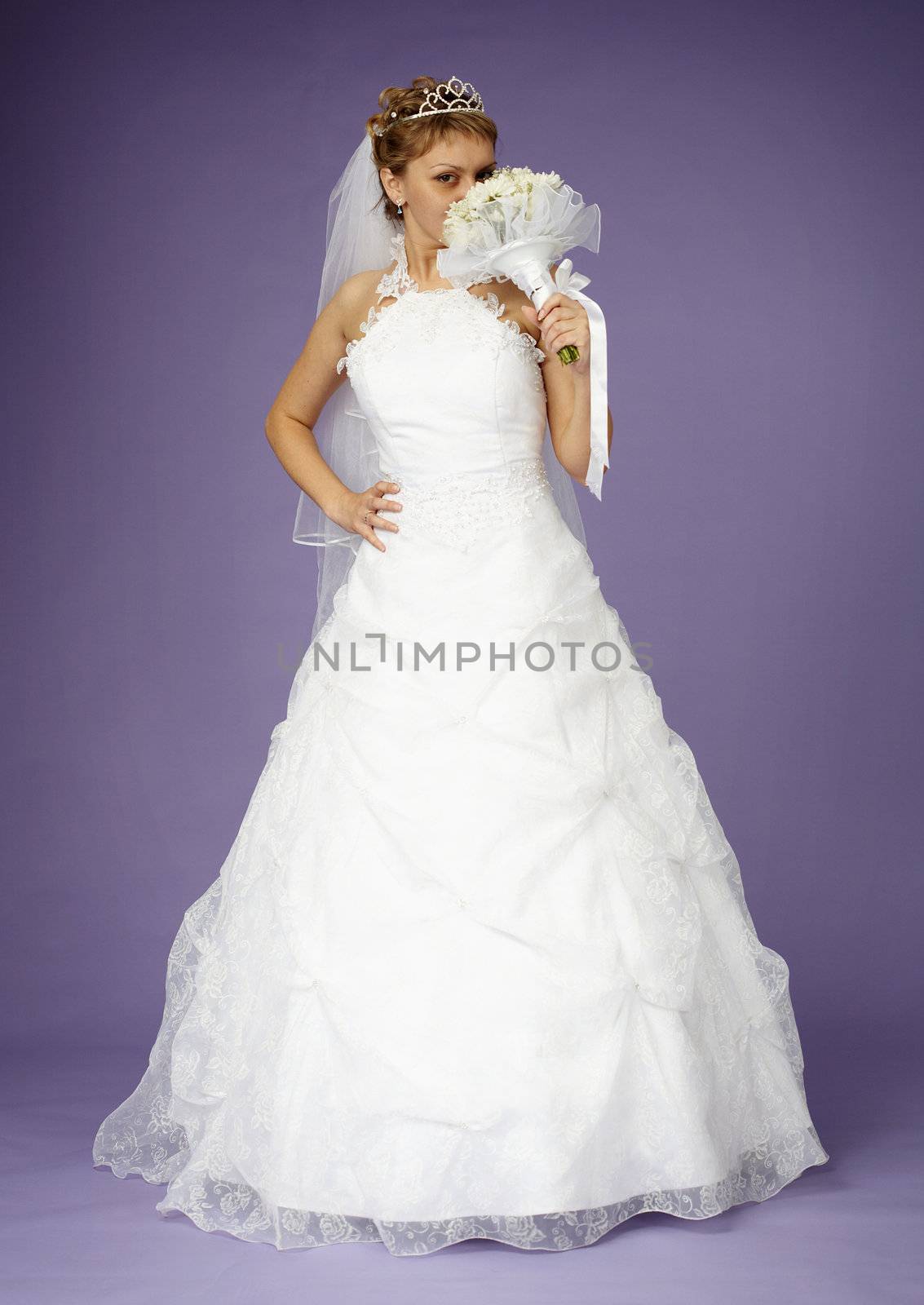 Young bride in a white dress with a bouquet on purple background