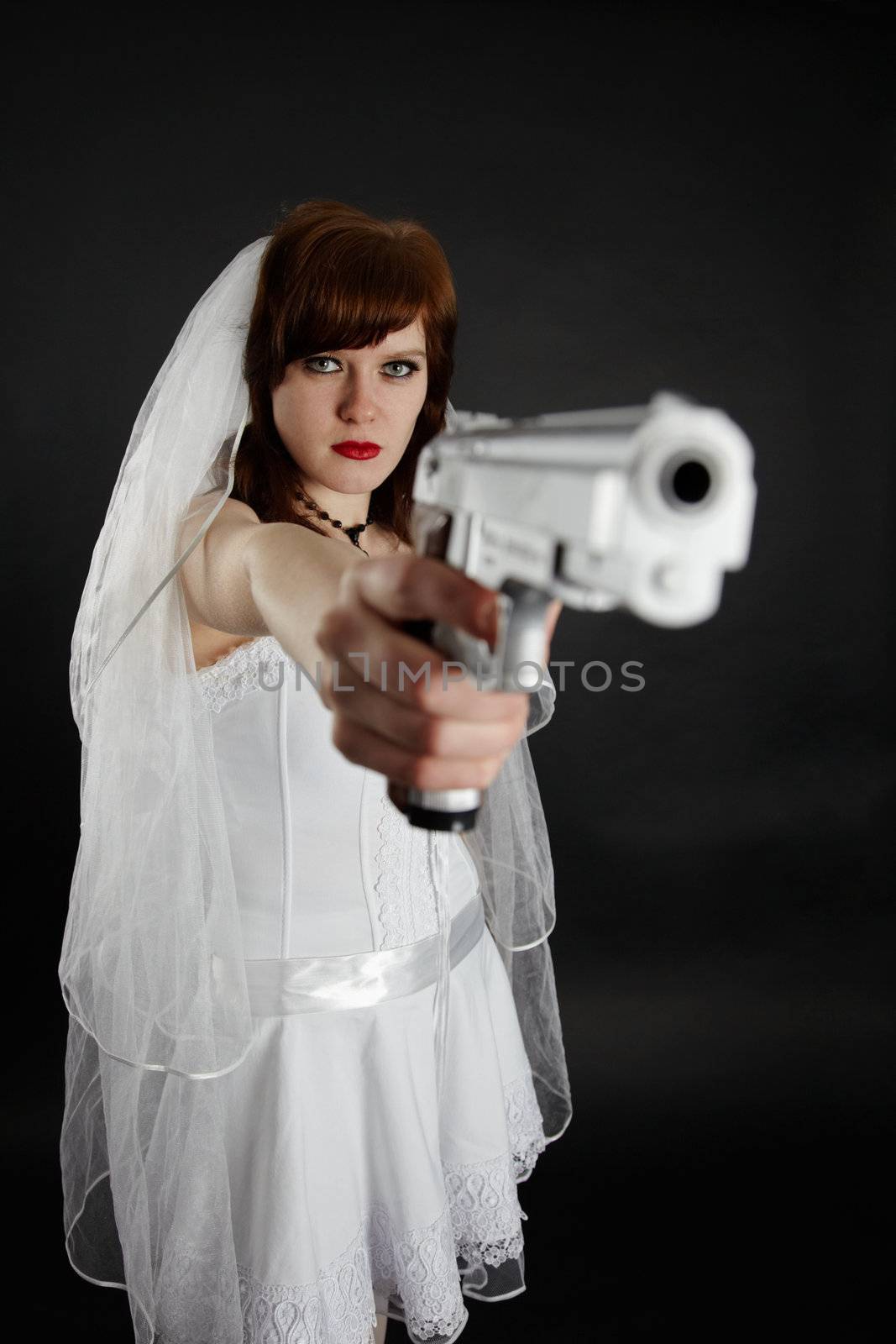 Serious bride take aim with a big pistol on black background