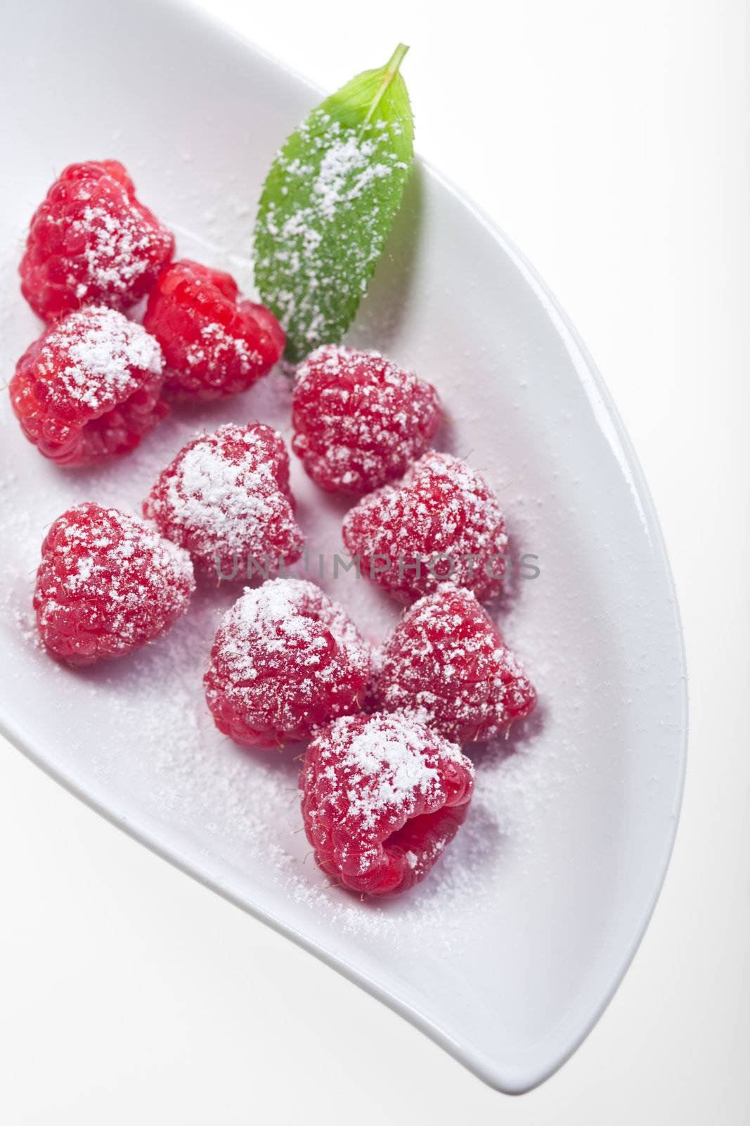 raspberries with icing sugar on a plate by bernjuer