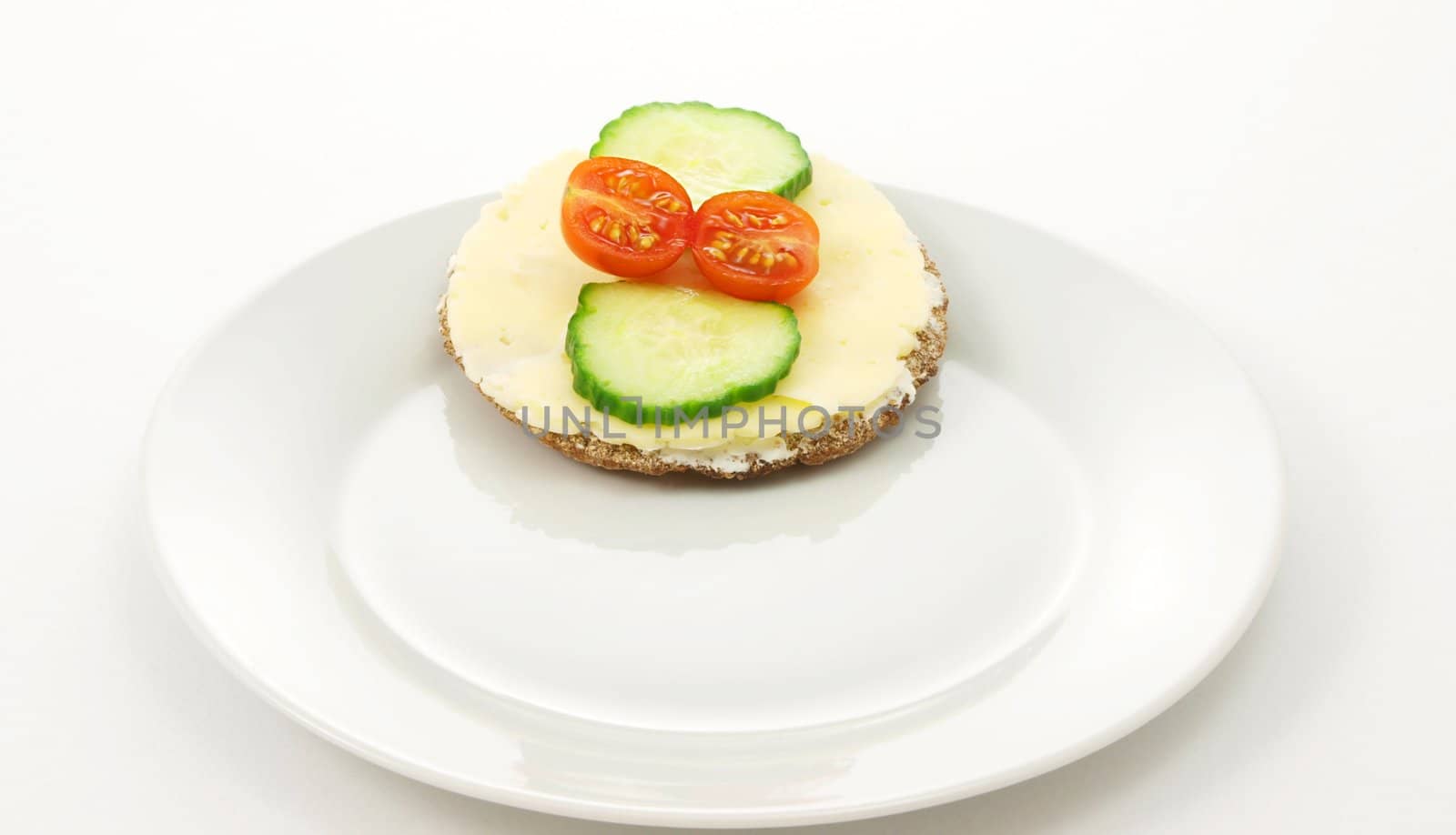 Cracker on plate, with tomato and cucumber, white background