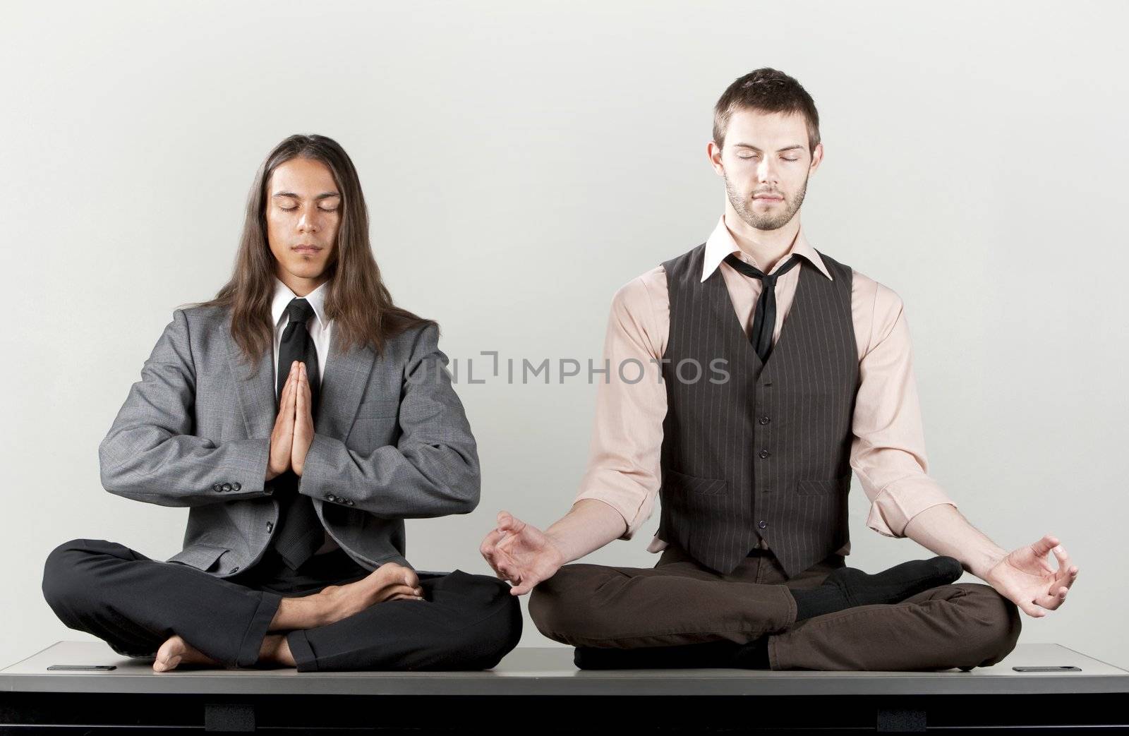 Two businessmen meditating on their office desk