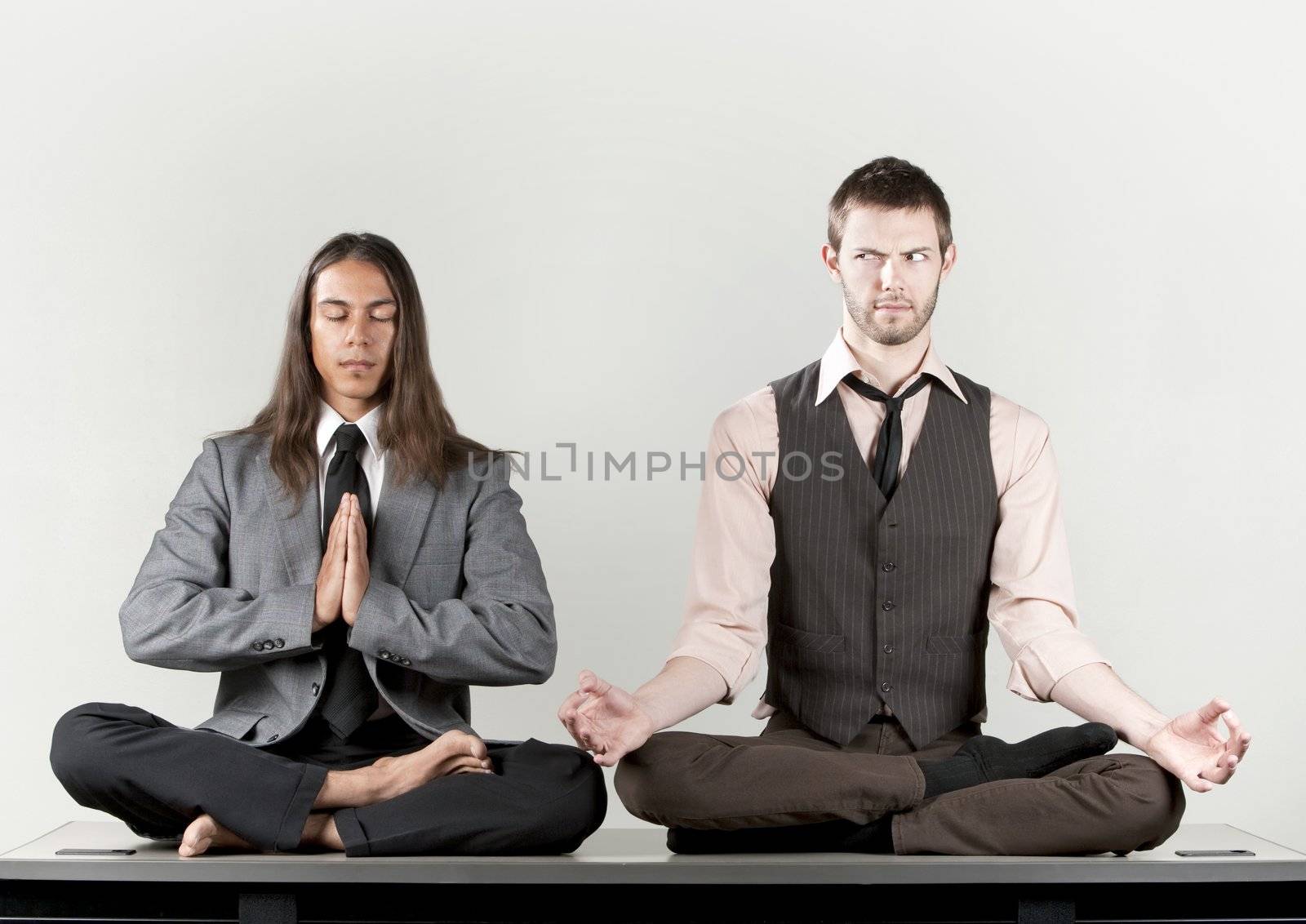 Two businessmen meditating on their office desk