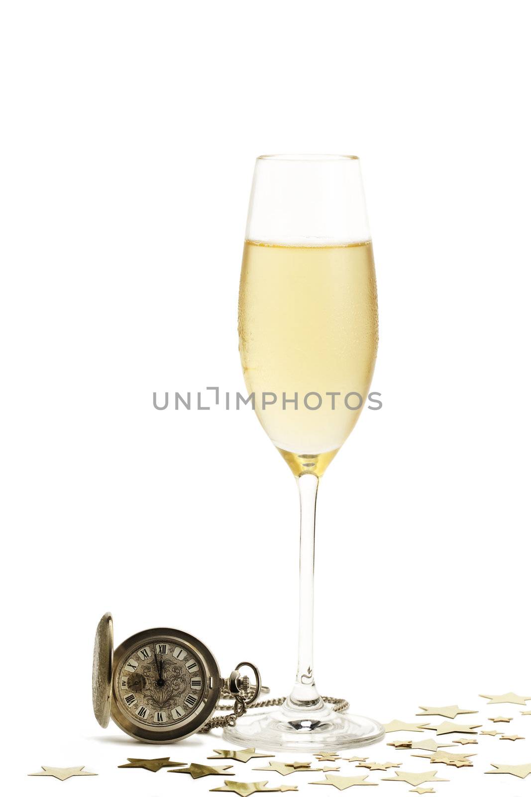 cold glass of champagne with a old pocket watch and metal stars on white background