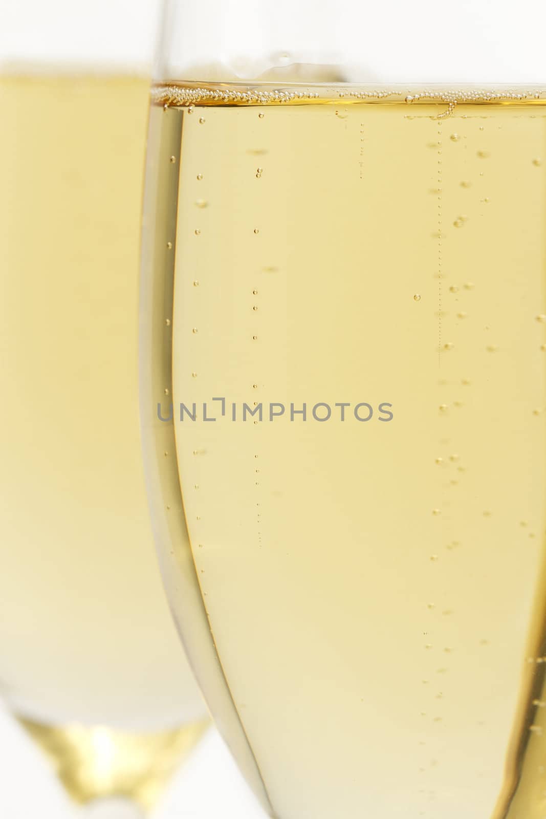 glass with champagne closeup in front of other on white background