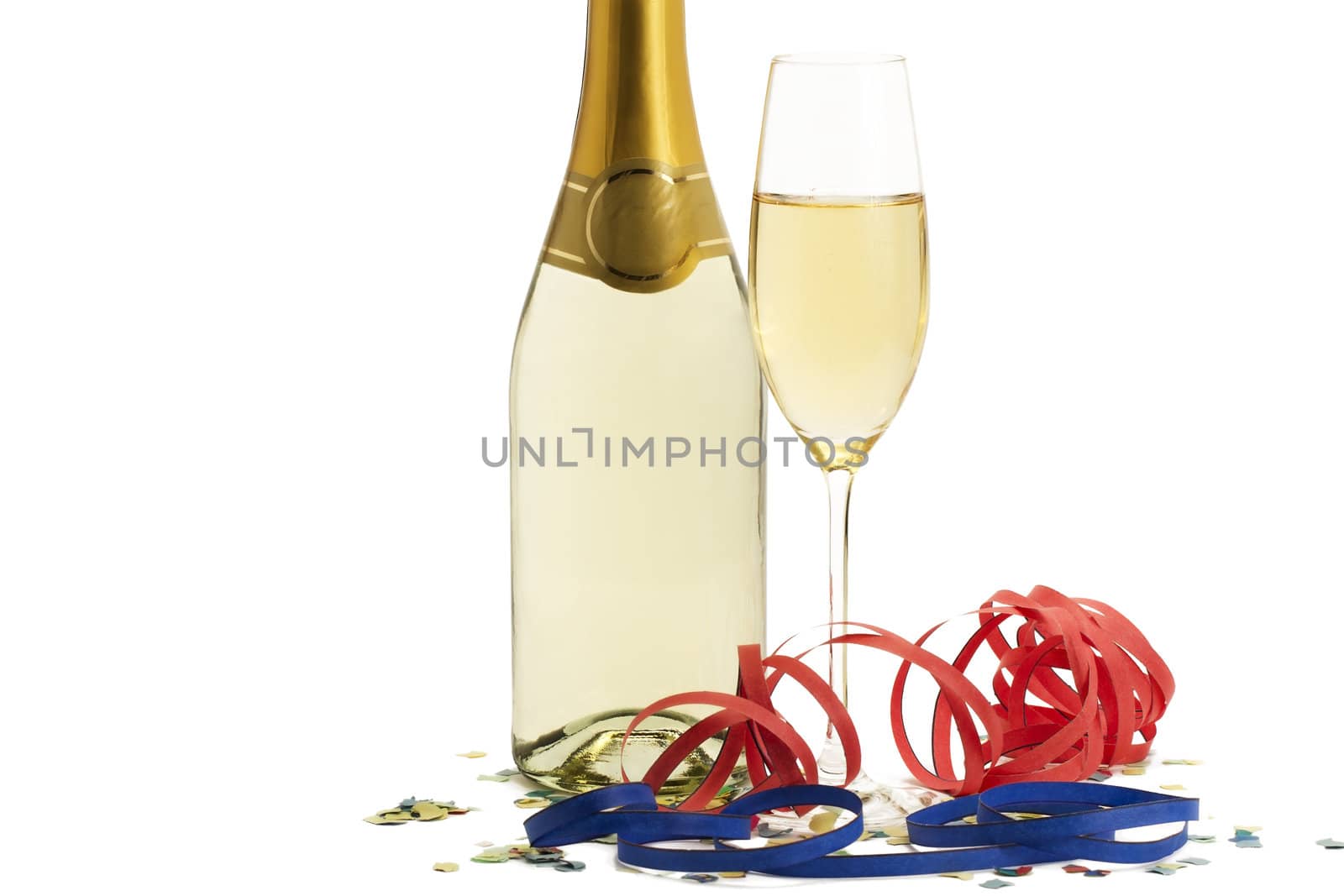 glass of champagne with blow-outs and confetti in front of a champagne bottle on white background