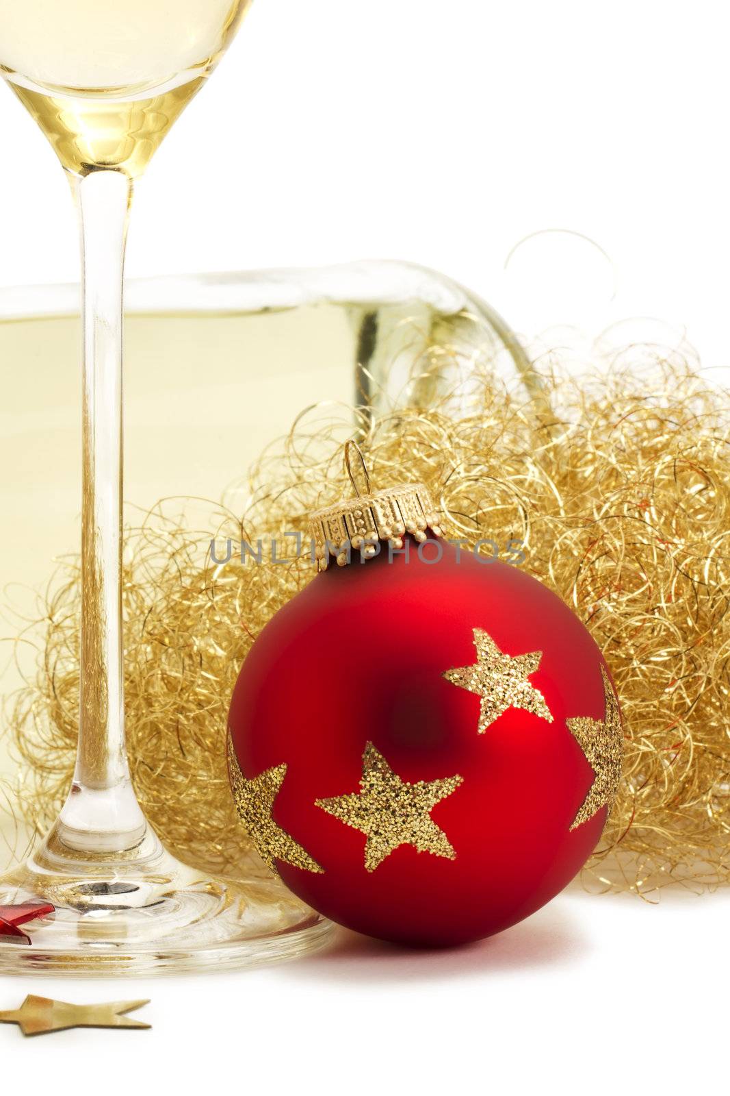 red christmas ball near glass with champagne, angels hair in front of a champagne bottle on white