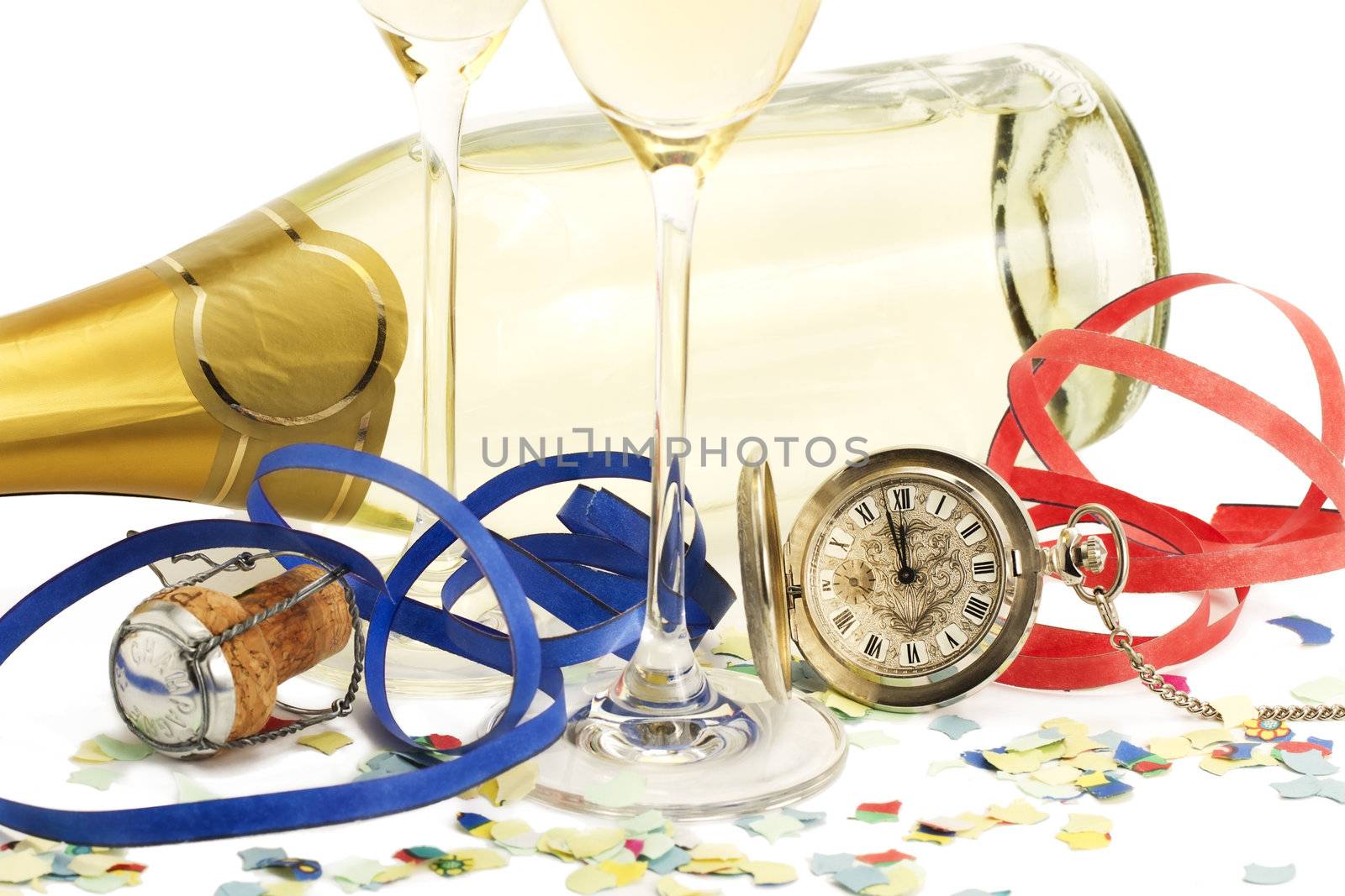 two glasses with champagne, old pocket watch, streamer, cork and confetti in front of a champagne bottle on white background