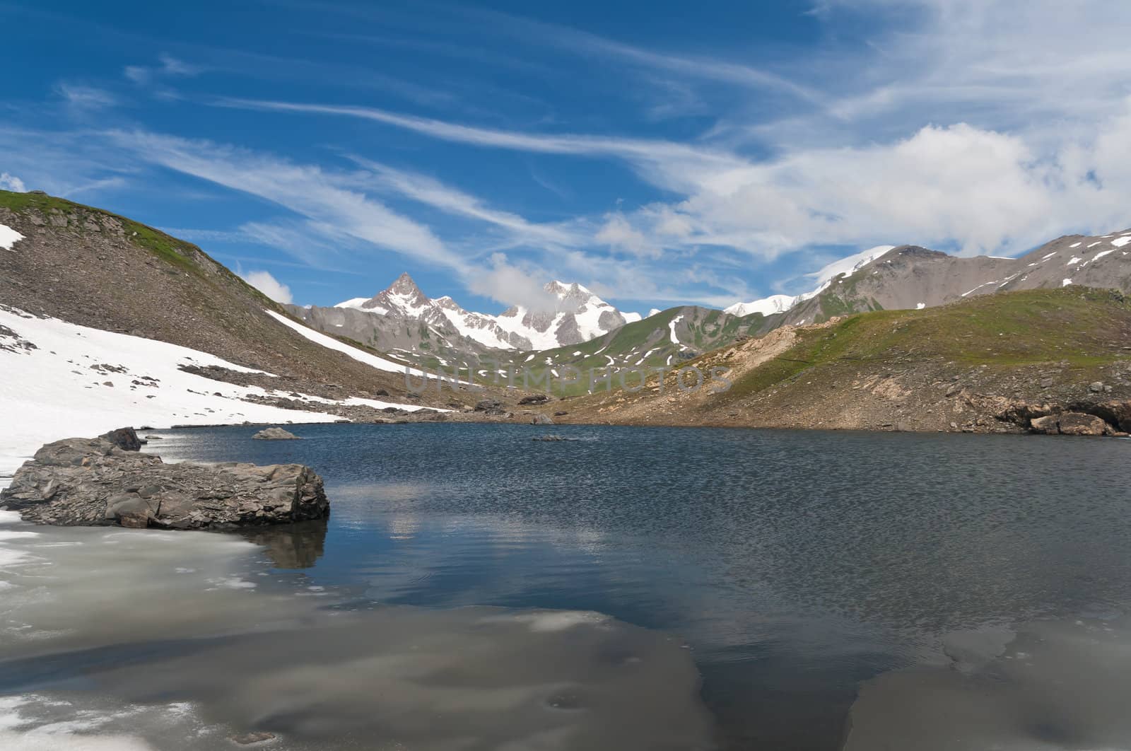small lake in  Pointe Rousse pass, Aosta valley, Italy with Mont Blanc massif on background