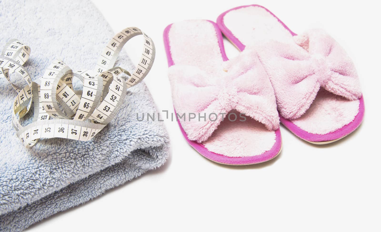 slippers, grey folded towel and metr on white