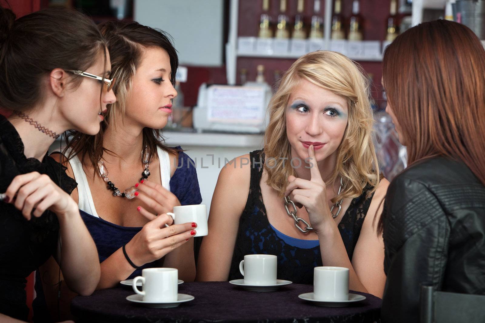 Young cute girls sharing a secret in a cafe