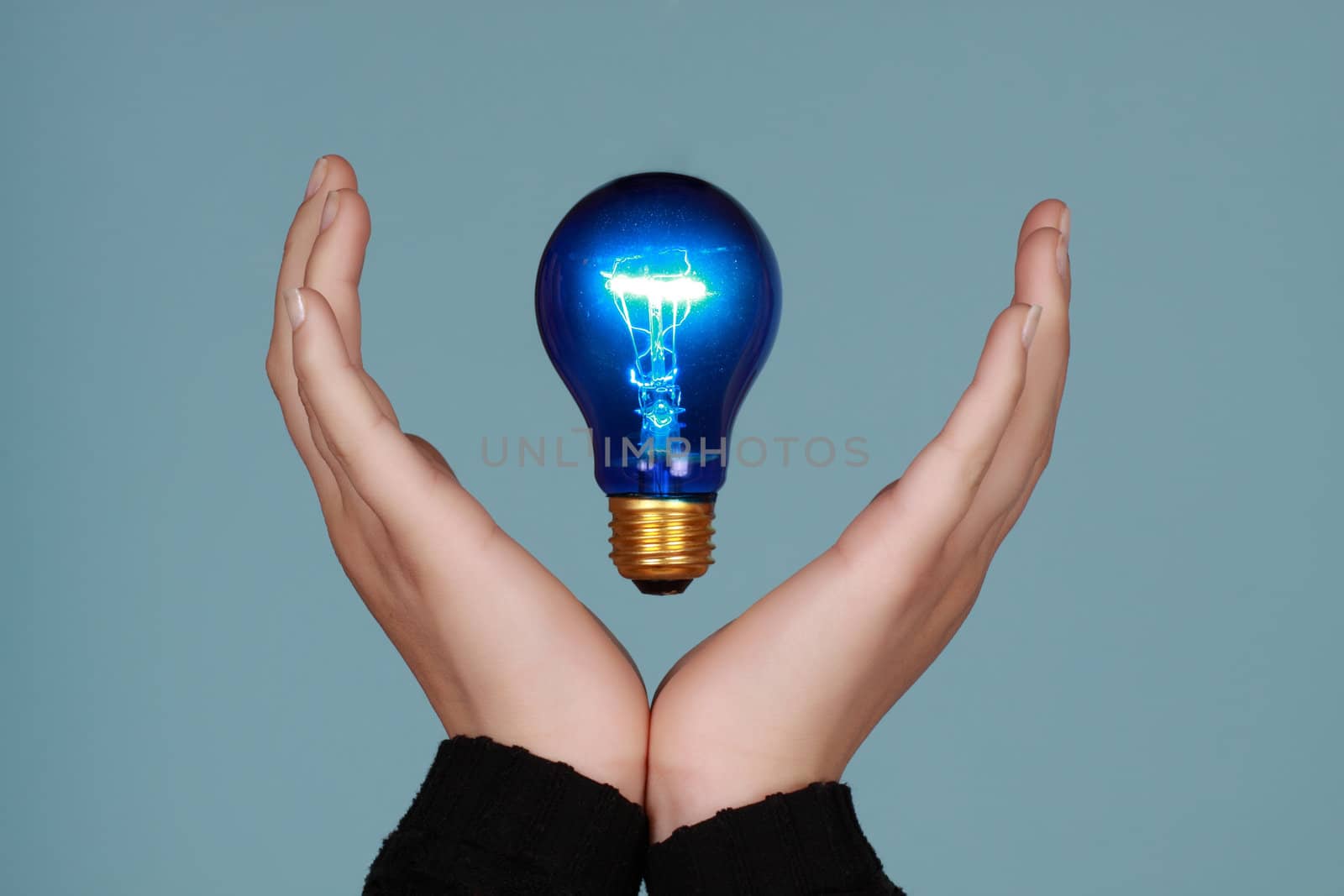 hands framing a blue lightbulb