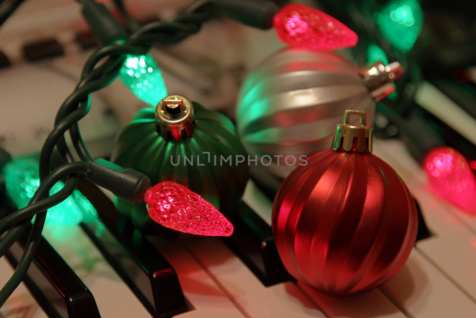 Three Christmas baubles and Christmas lights on piano keys. 