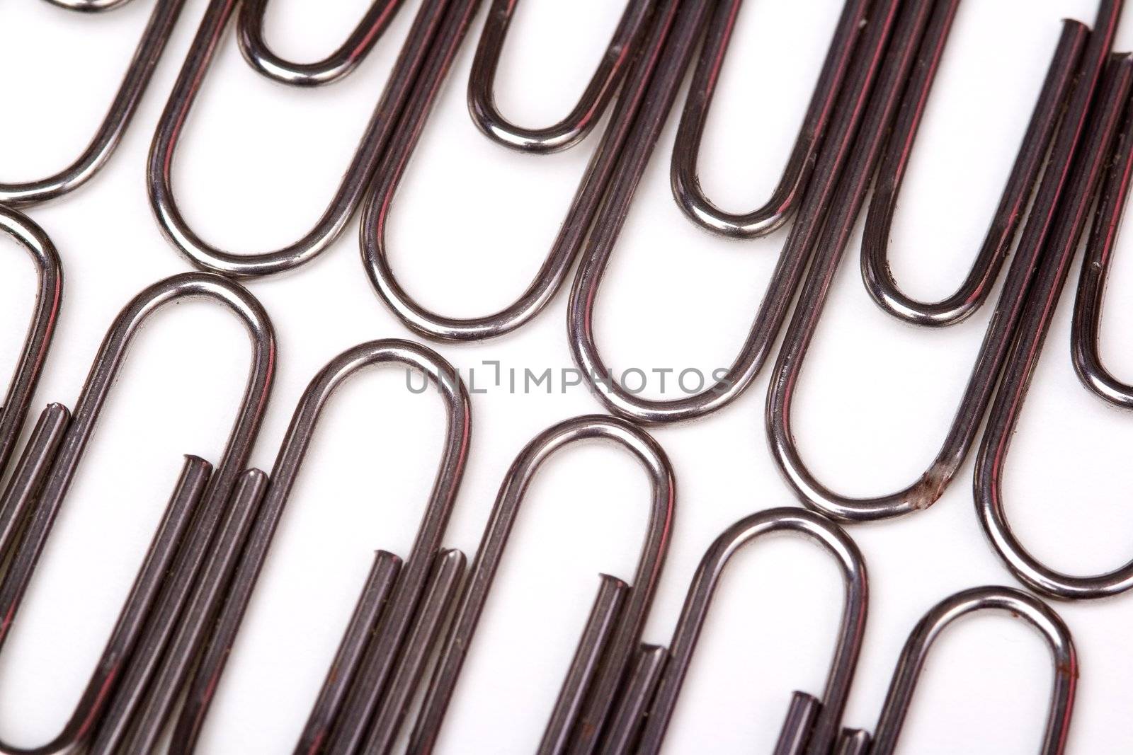 A lot of metal paperclips forming a pattern  on a white background